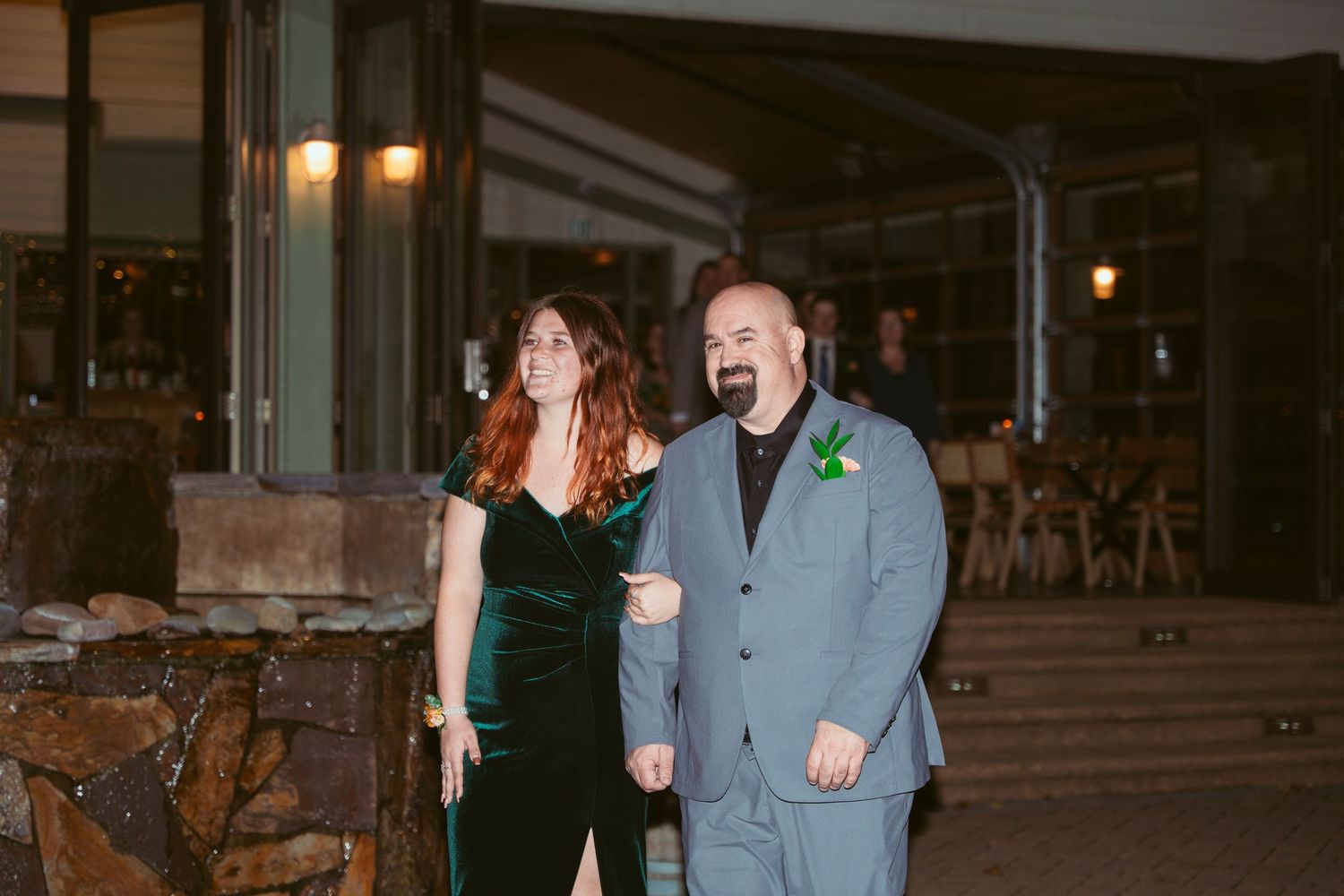 Guests mingling at a nighttime outdoor reception with atmospheric lighting.