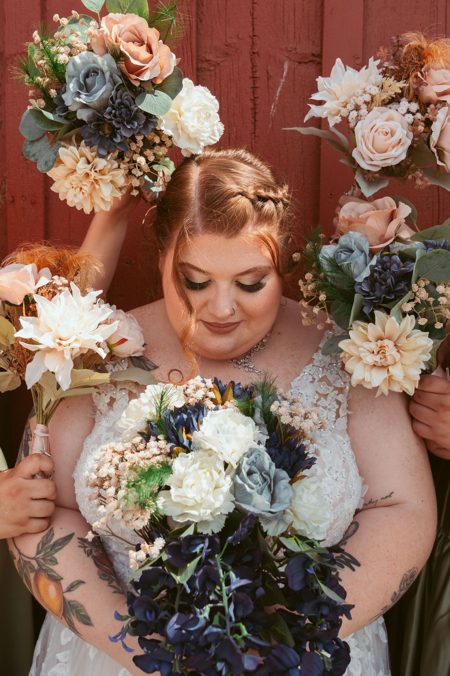 Beautiful wedding bouquets with peach, blue and white flowers arranged against a rustic red barn background.