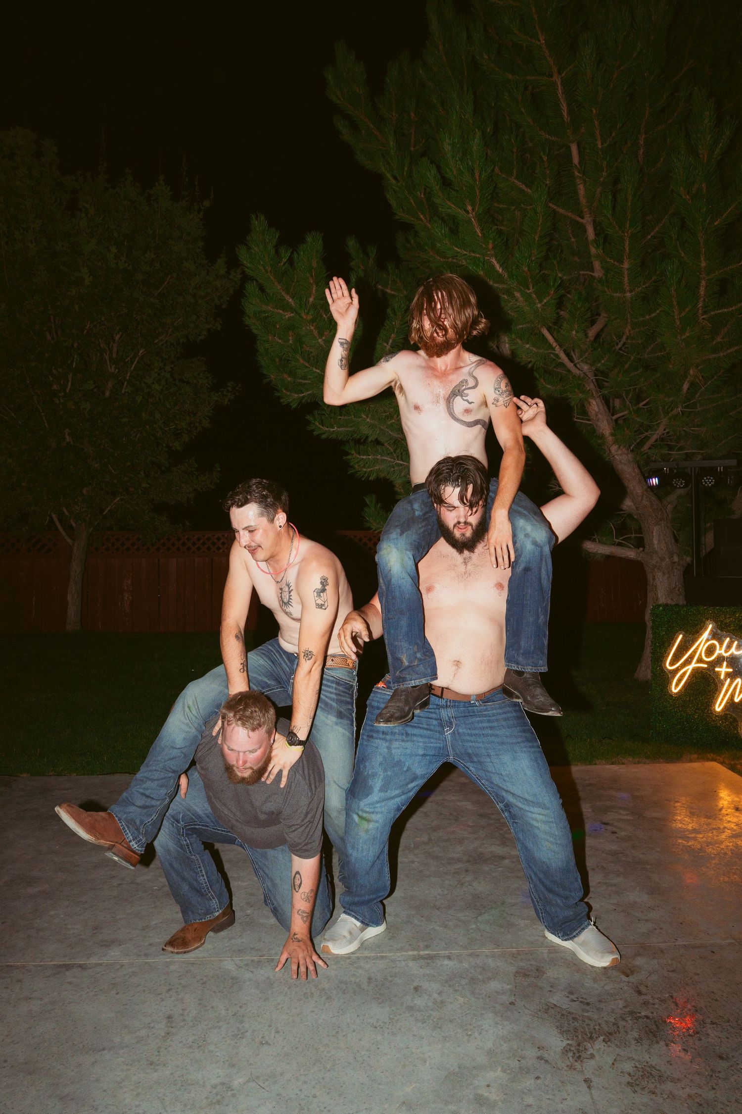 Energetic dancers performing acrobatic moves on a concrete patio at night.