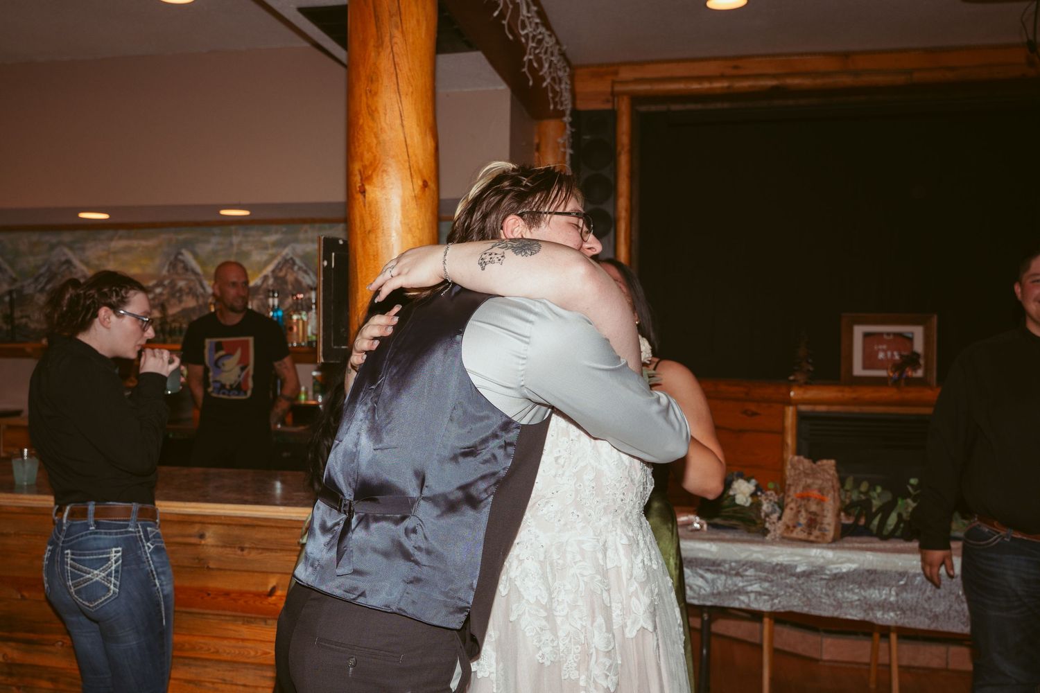 People dancing together in a rustic wooden venue with warm lighting and exposed wooden beams and columns.