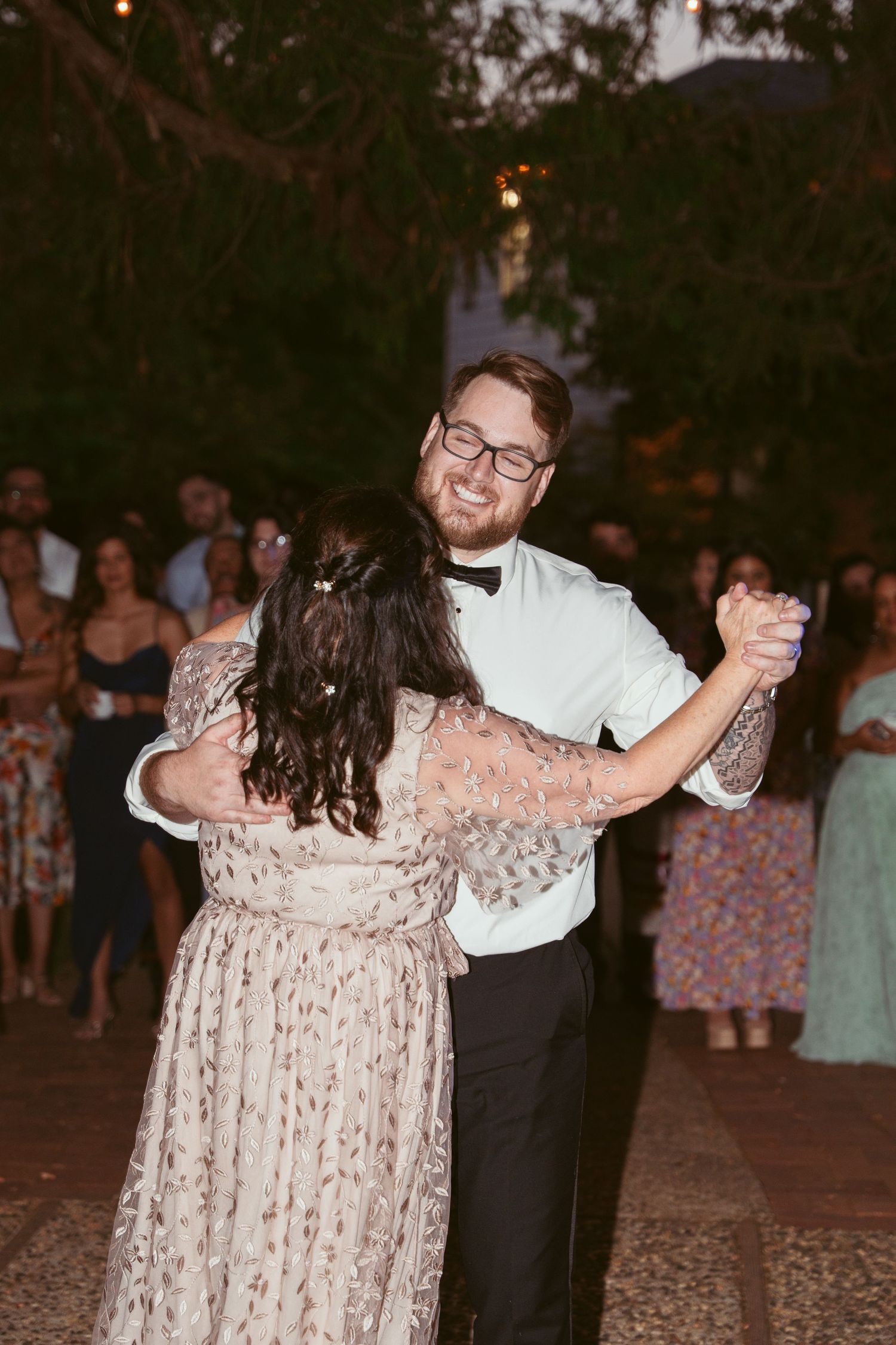 Couples twirling and dancing together during a lively outdoor wedding reception.
