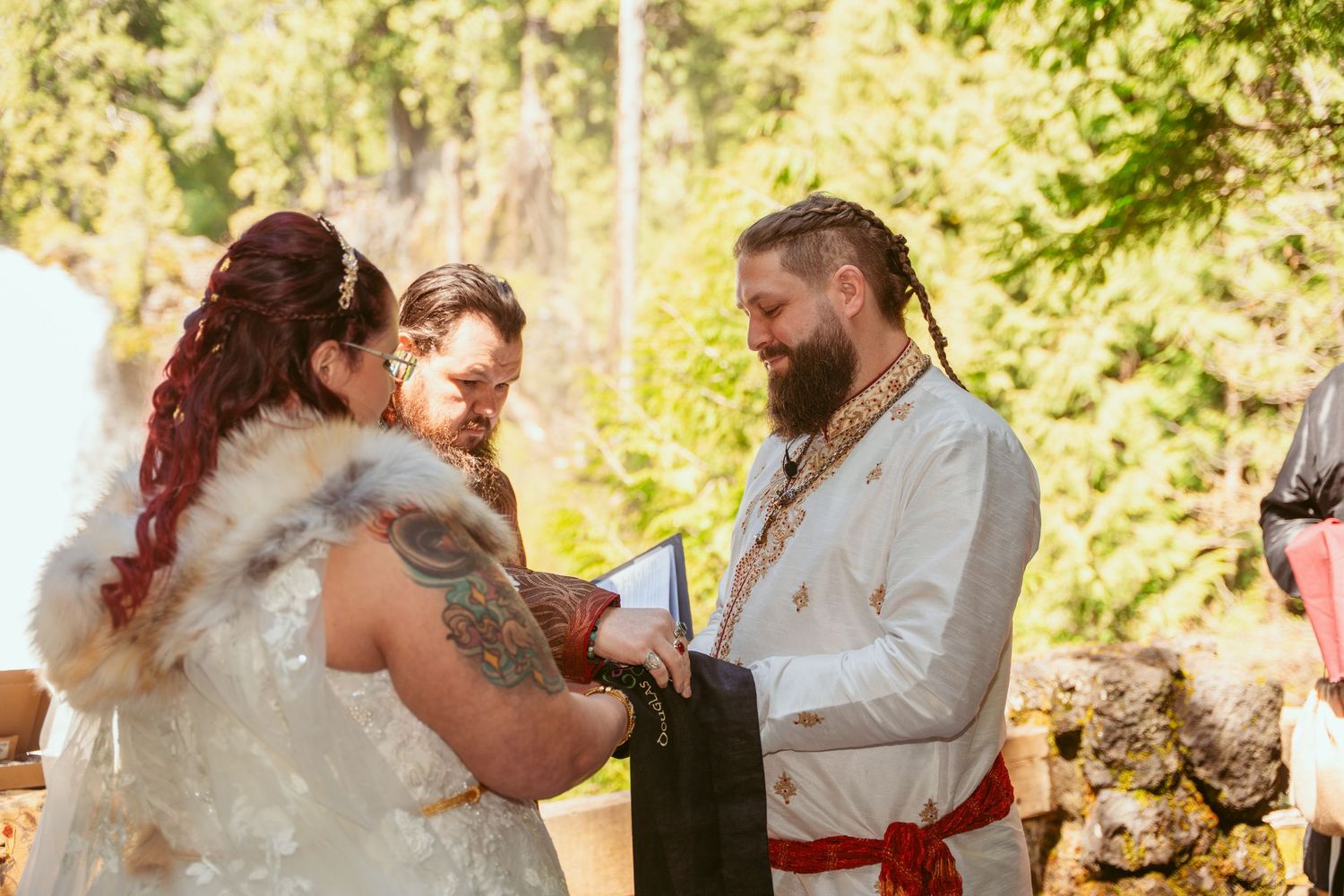 Outdoor wedding celebration with rustic forest backdrop and flowing white gown.