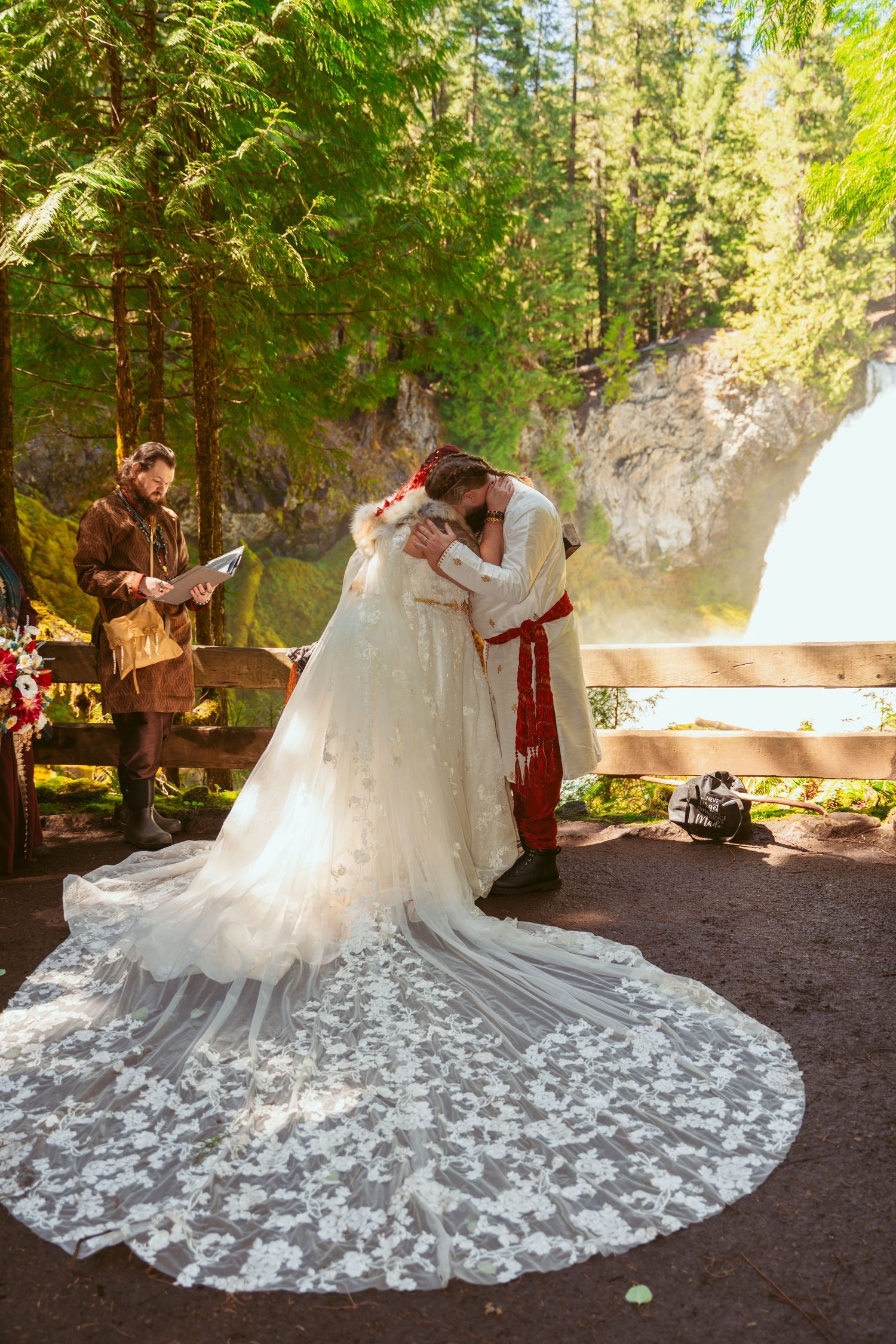 An elegant white wedding gown with intricate lace details displayed in a forest setting.
