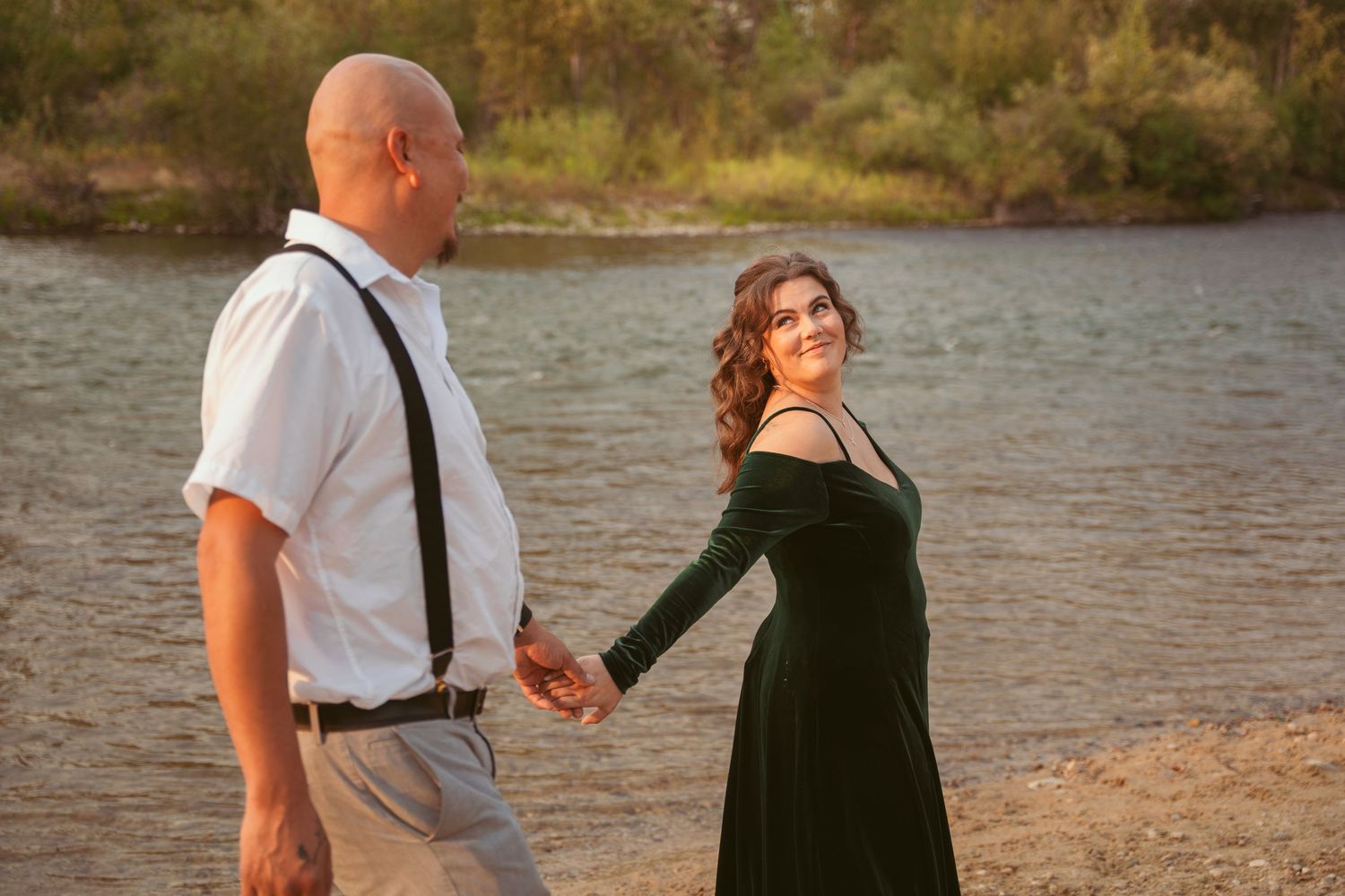 A couple shares a romantic moment by the water's edge at sunset.