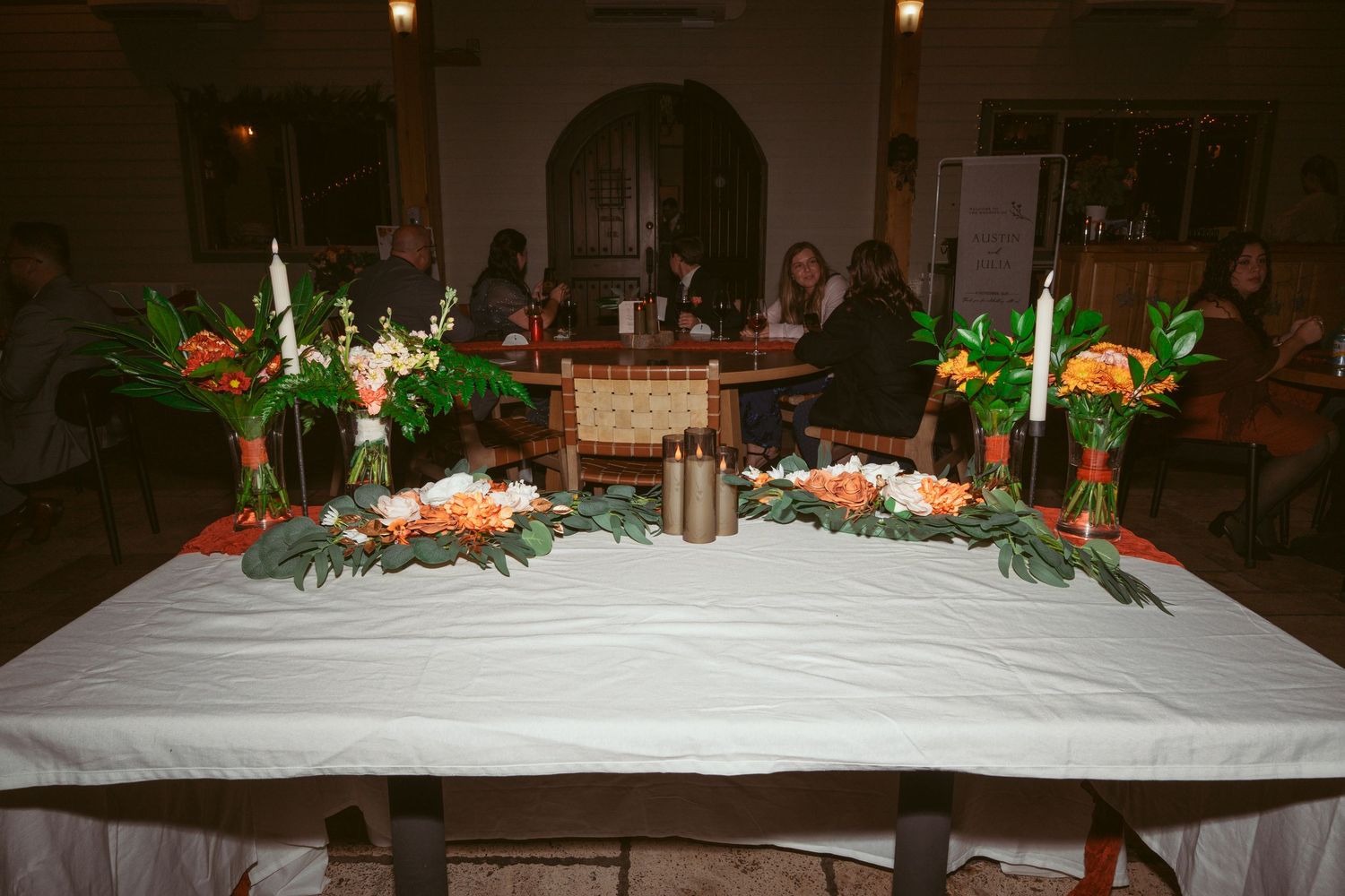 Long white banquet table adorned with floral centerpieces and glowing candles.