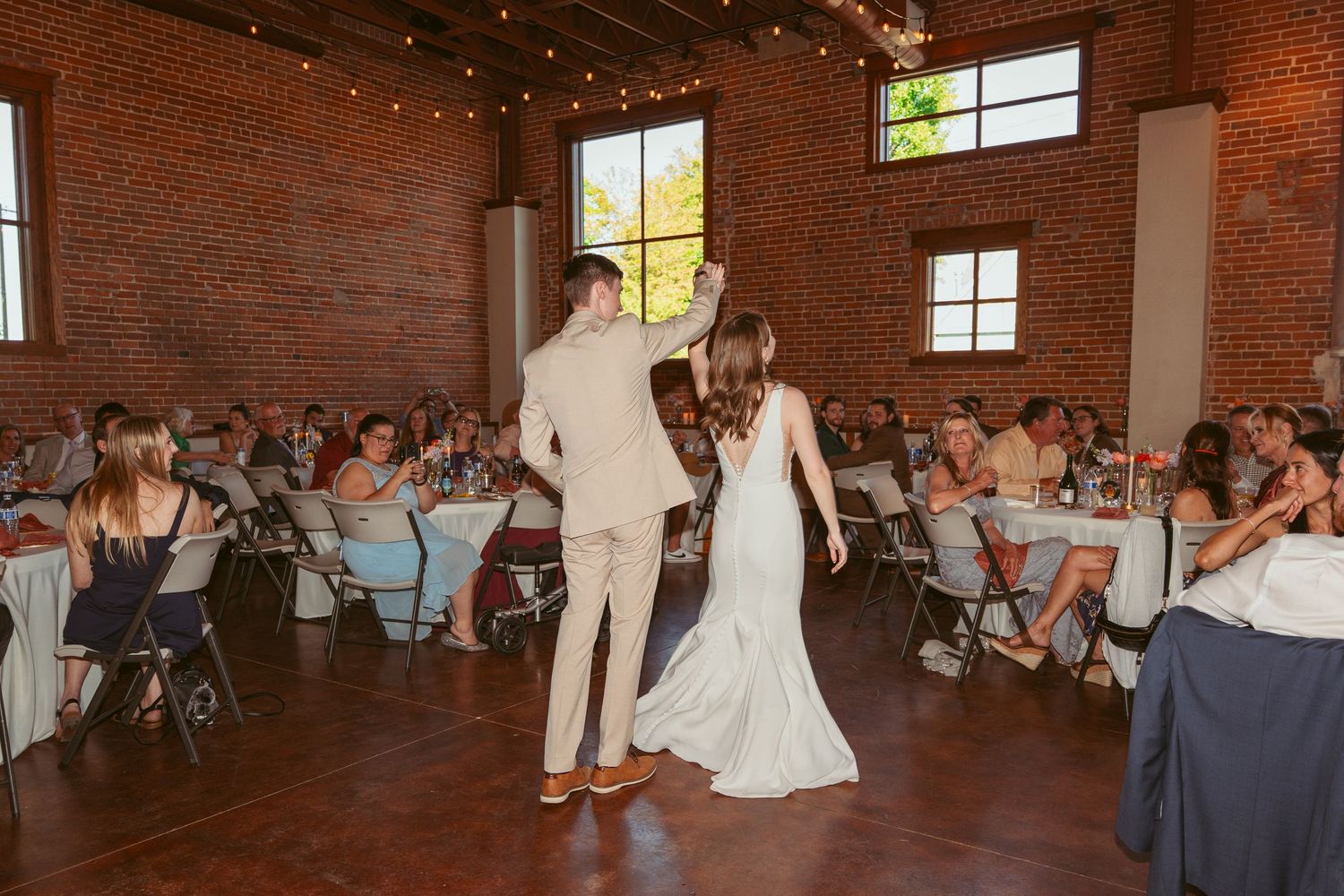 Wedding reception in a charming industrial venue with exposed brick walls and natural lighting.