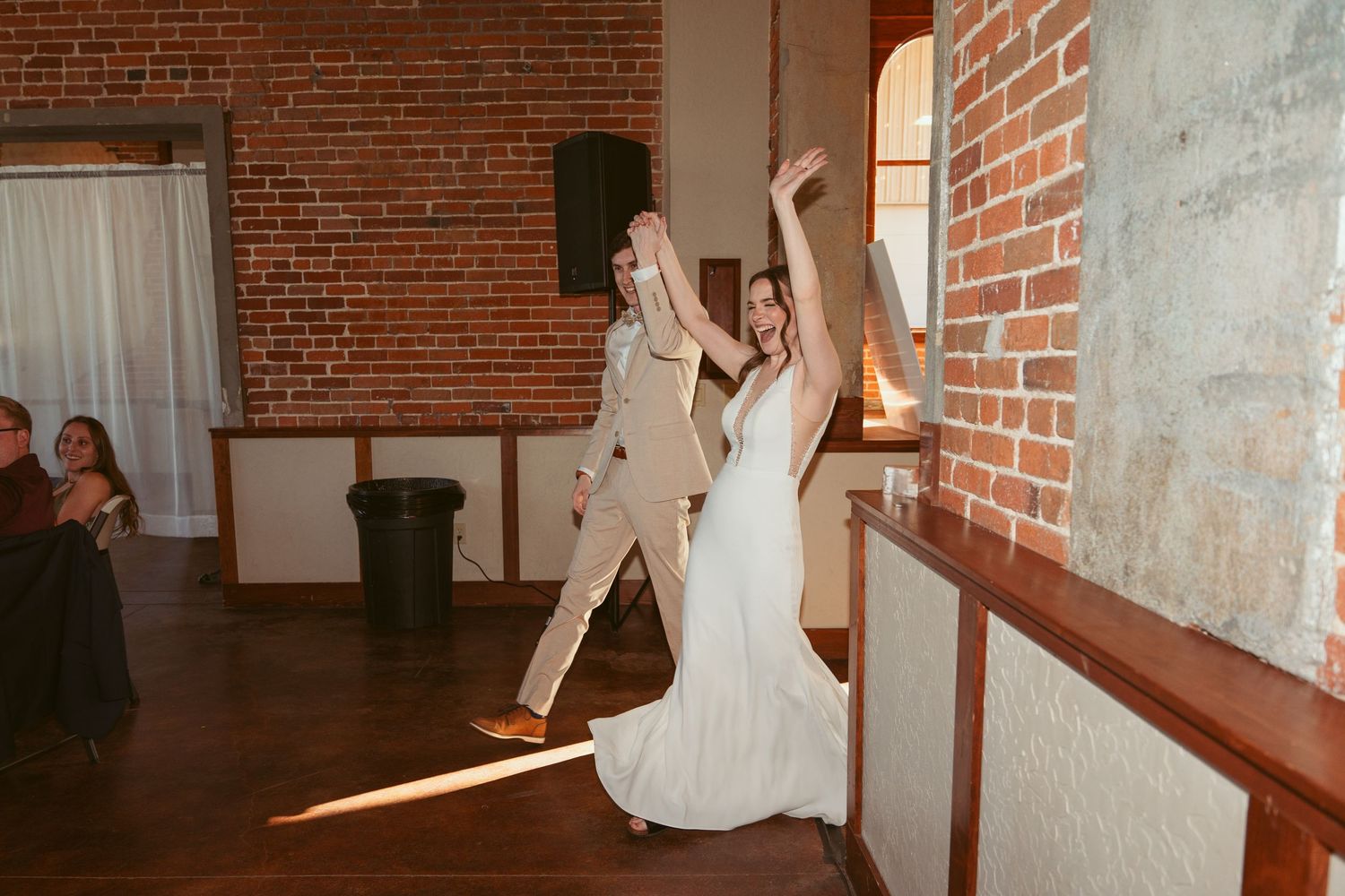 Wedding guests dancing and celebrating in a historic brick building with wooden accents.