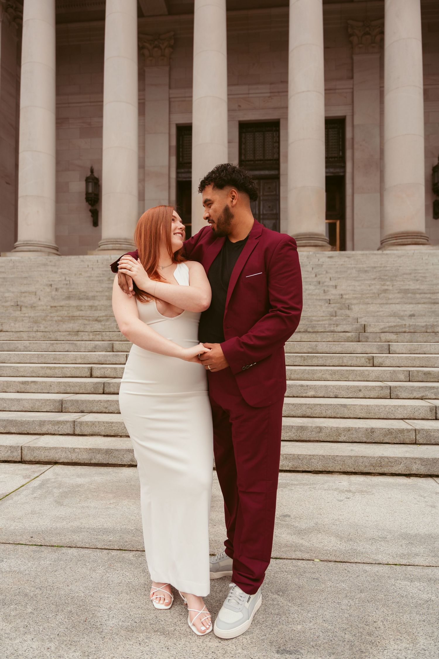 Couple in formal attire dancing on the steps of a historic building with white columns.