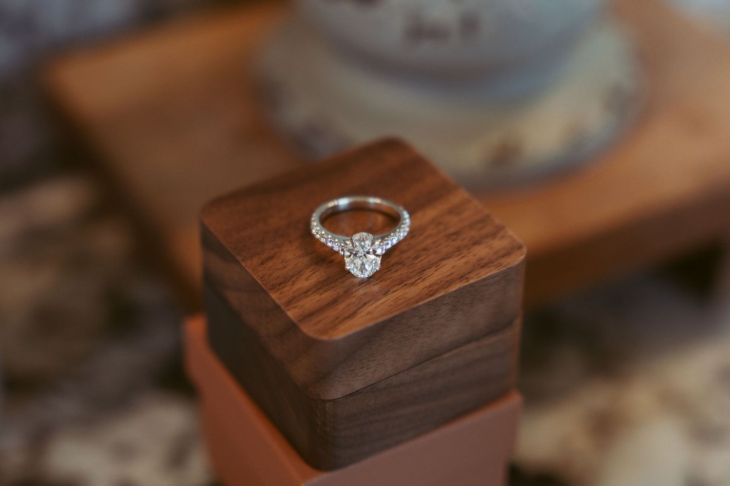 Diamond engagement ring displayed on wooden blocks in natural lighting.