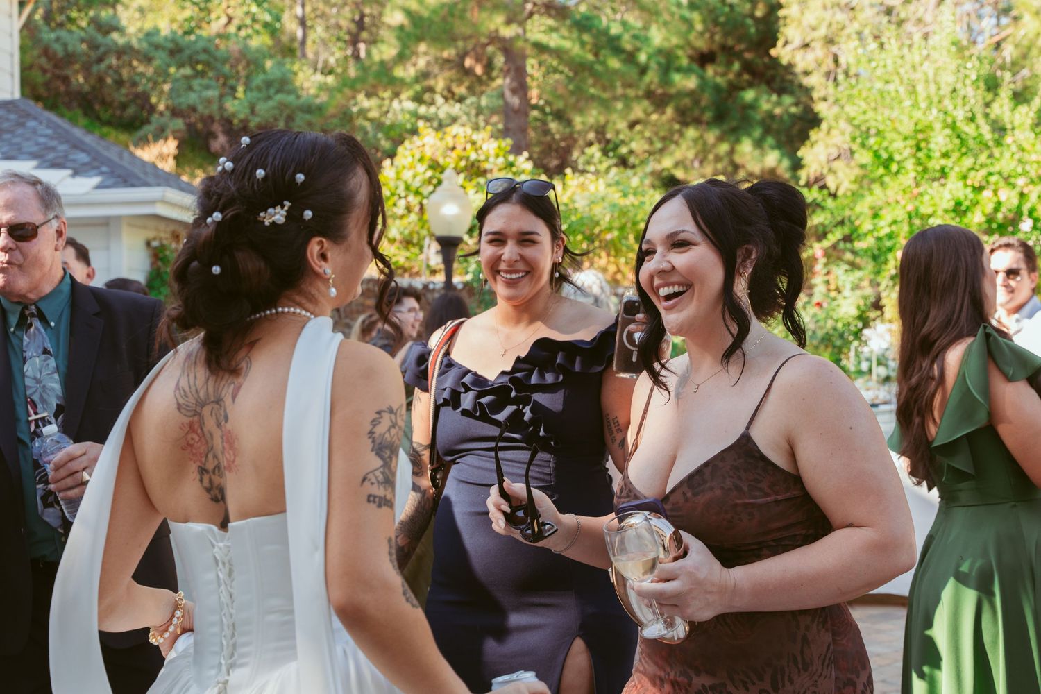 Wedding party members in green and white dresses mingling outdoors during daytime.