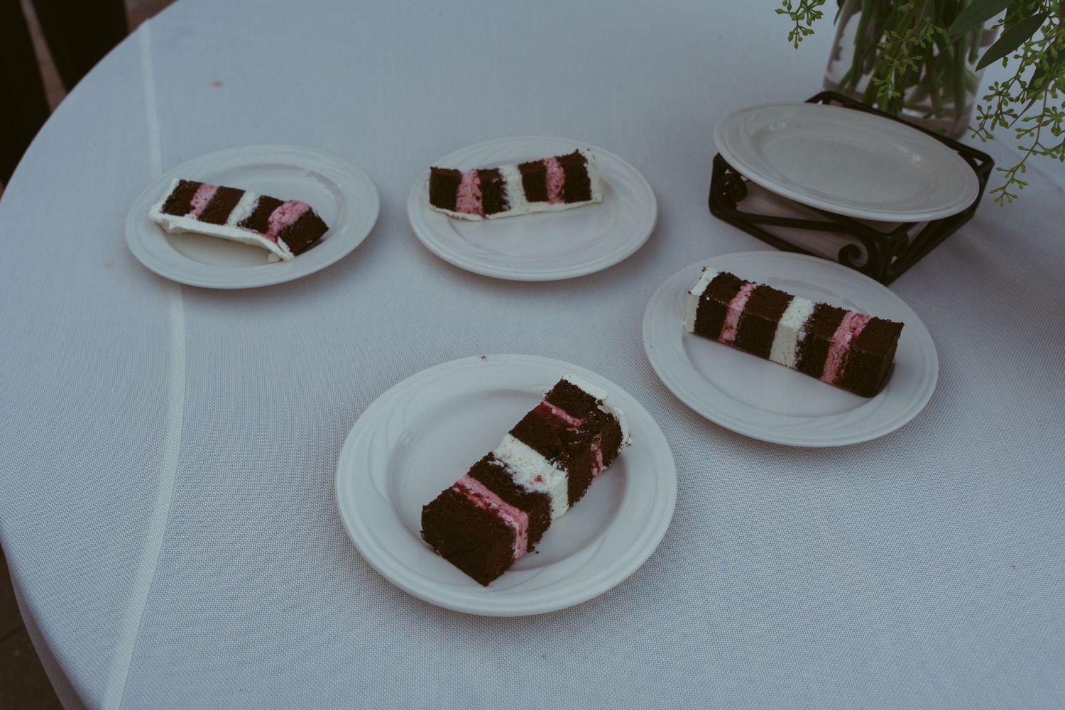 White plates with slices of layered chocolate cake arranged on a dining table.