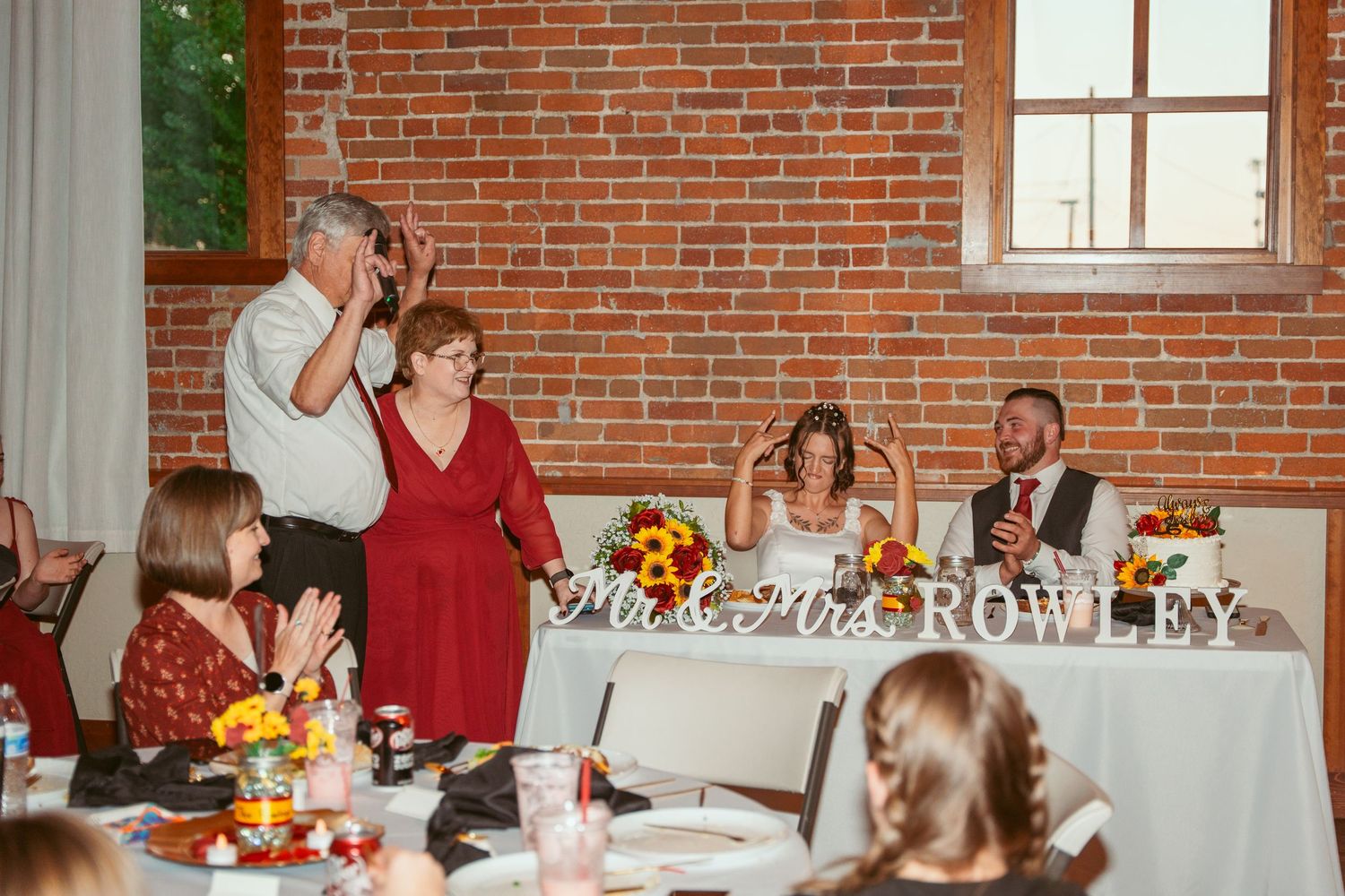 Wedding celebration in historic brick building with white linens and sunflower decorations.