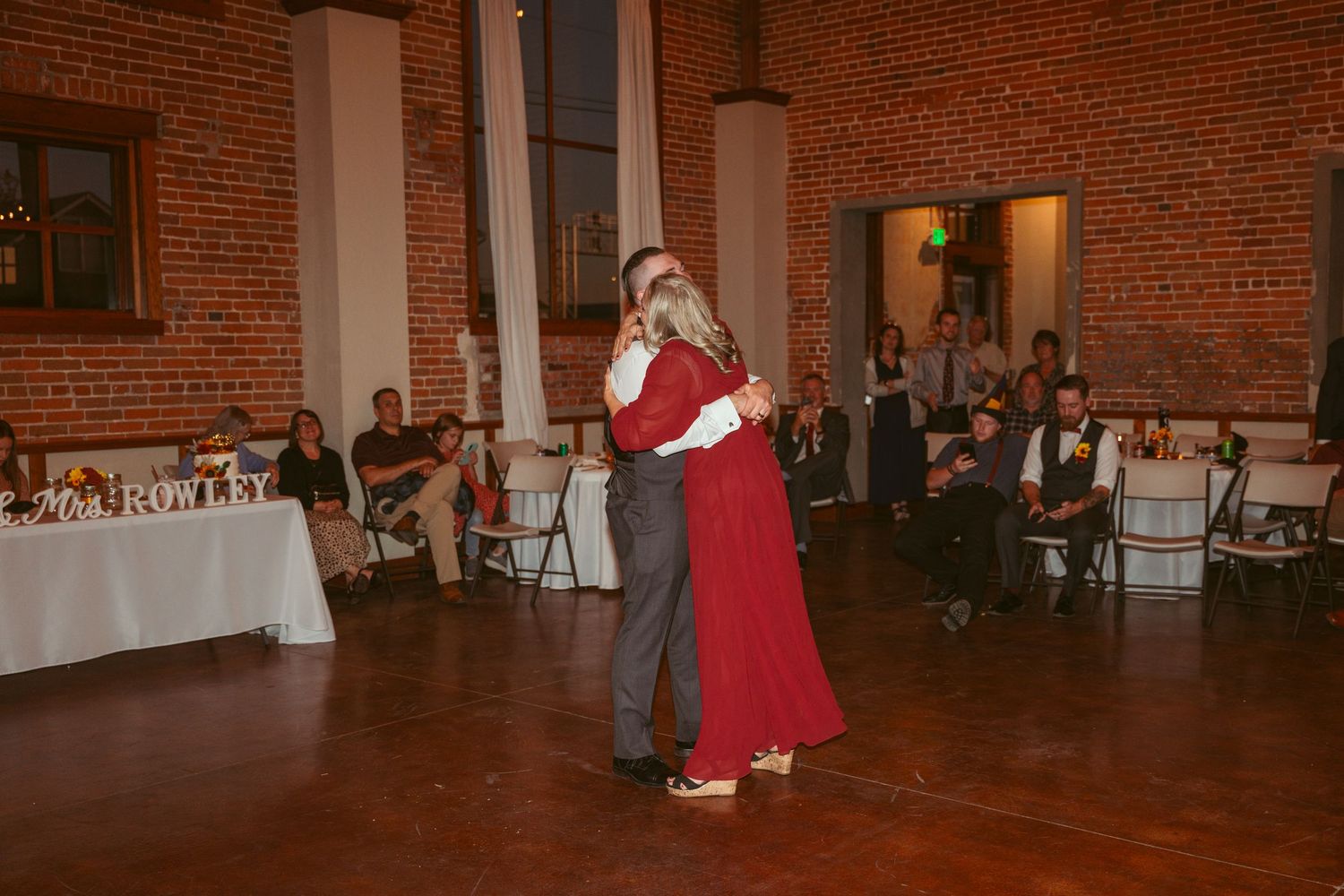 Evening celebration in historic brick venue with hardwood floors and decorative lighting.