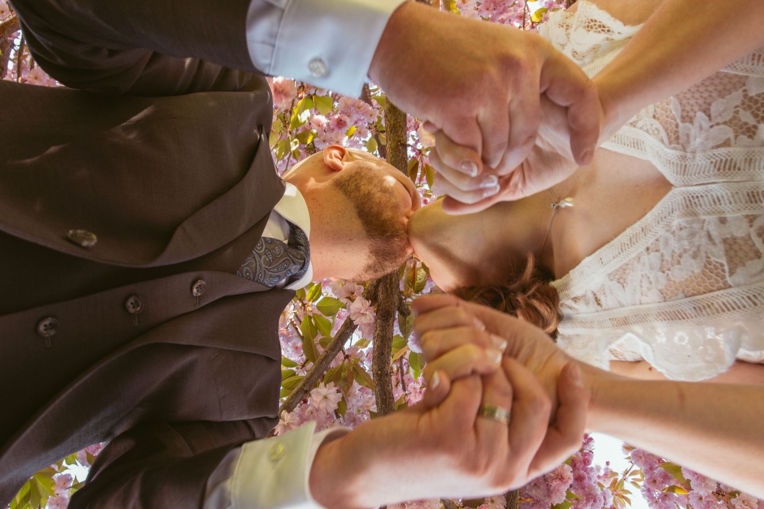 Close-up of wedding couple's hands exchanging rings during outdoor ceremony.