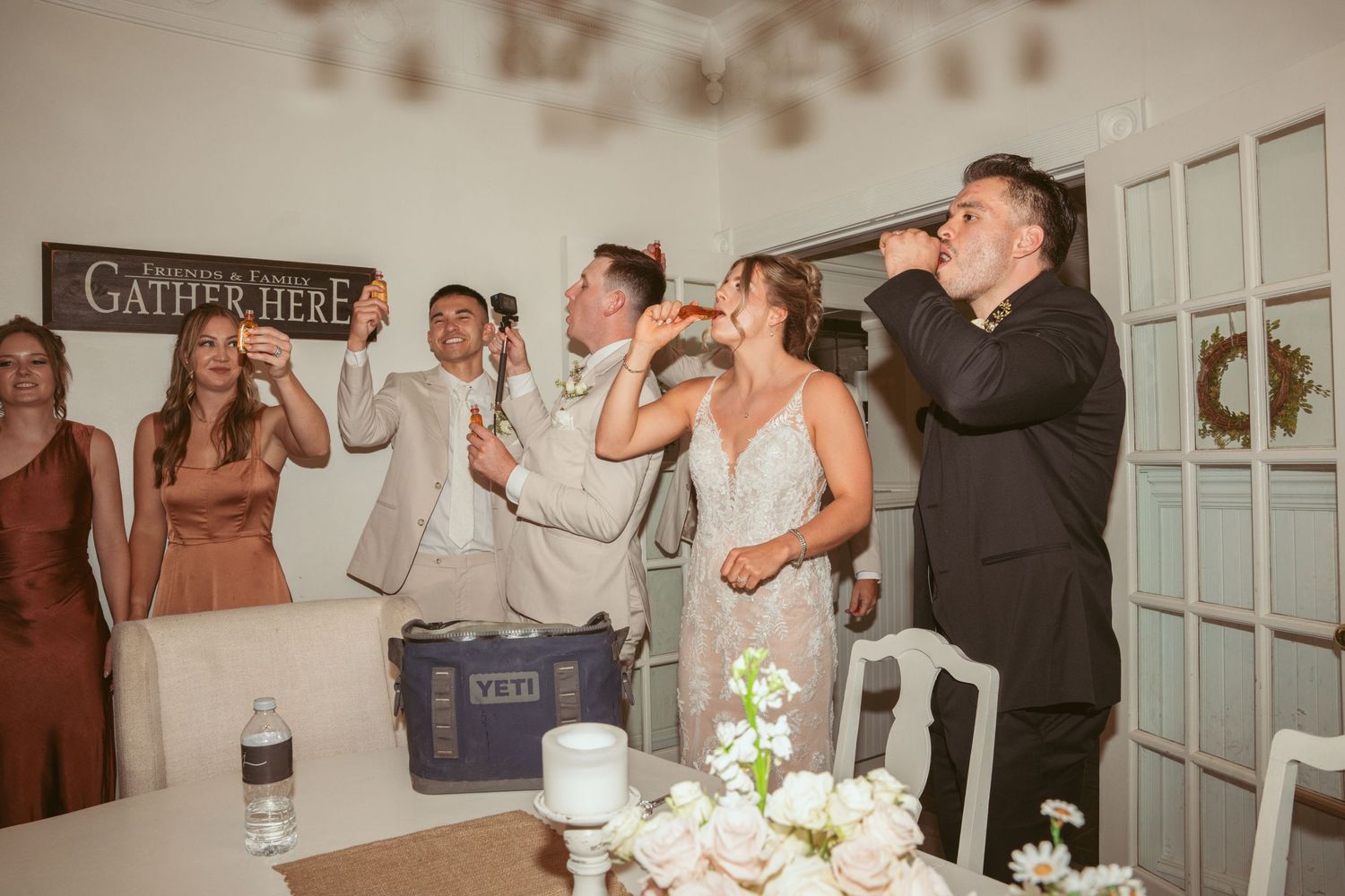 Wedding celebration candid moments captured inside a rustic venue with white walls.