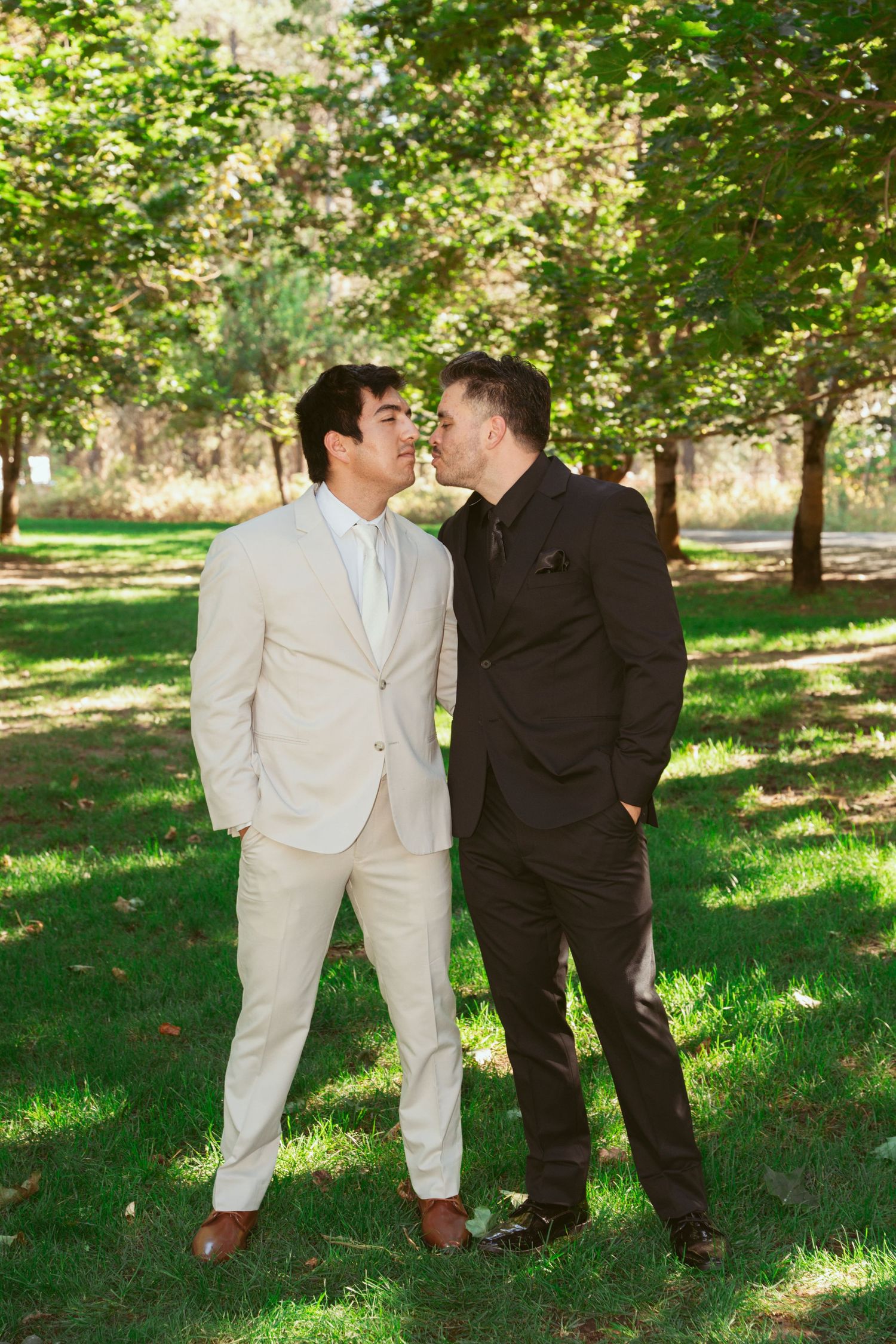 Two people in contrasting suits share laughs during an outdoor photo session.
