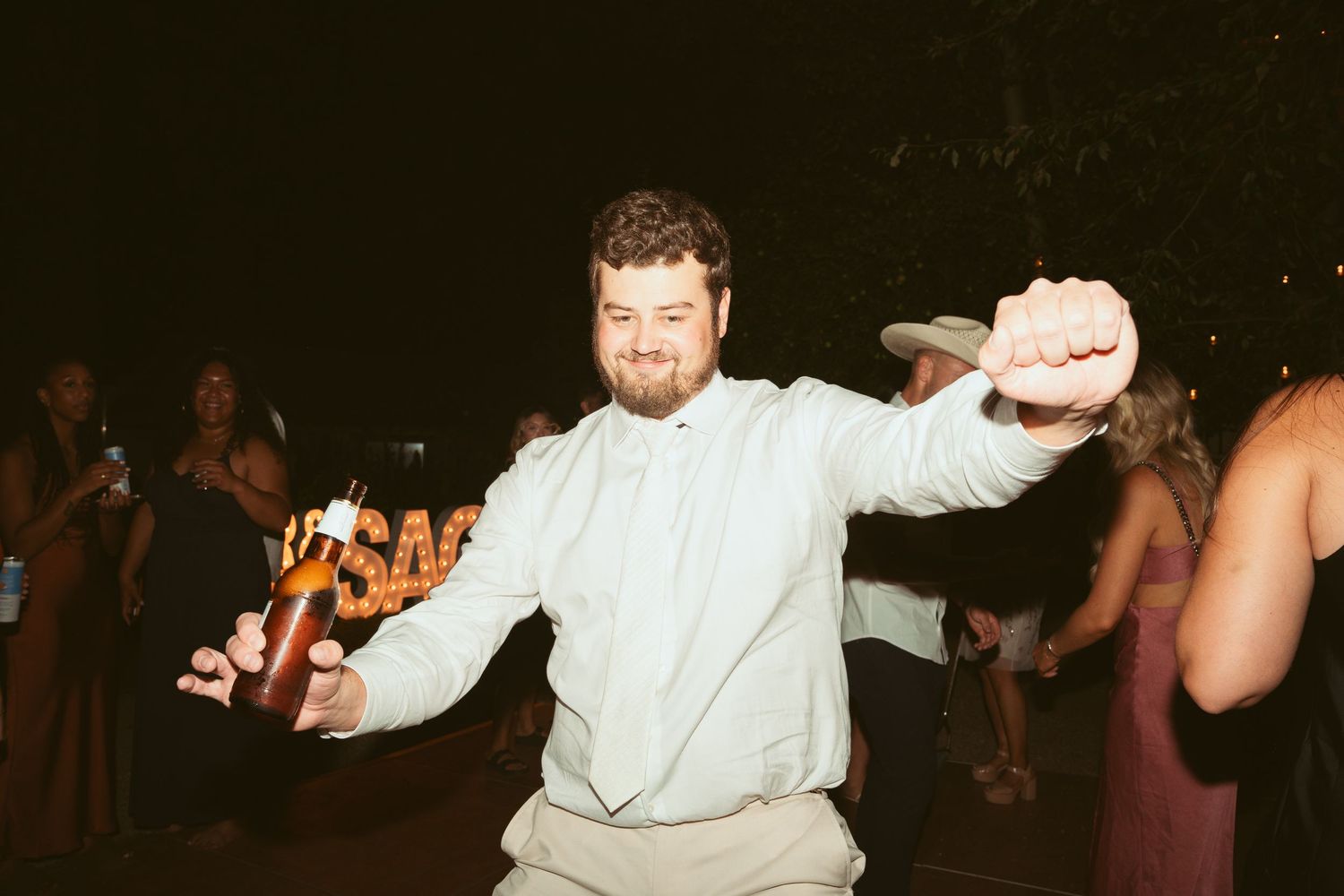 People dancing enthusiastically at an outdoor evening celebration.