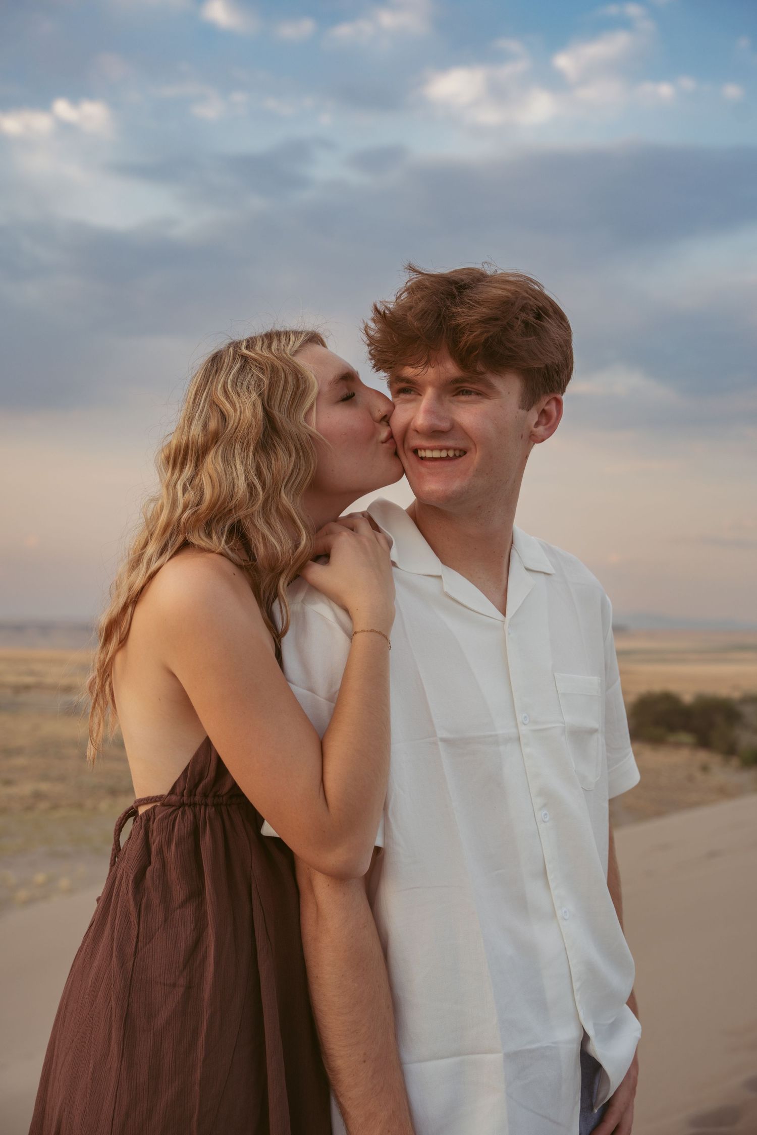 A sweet moment shared between a couple on a desert road at dusk.