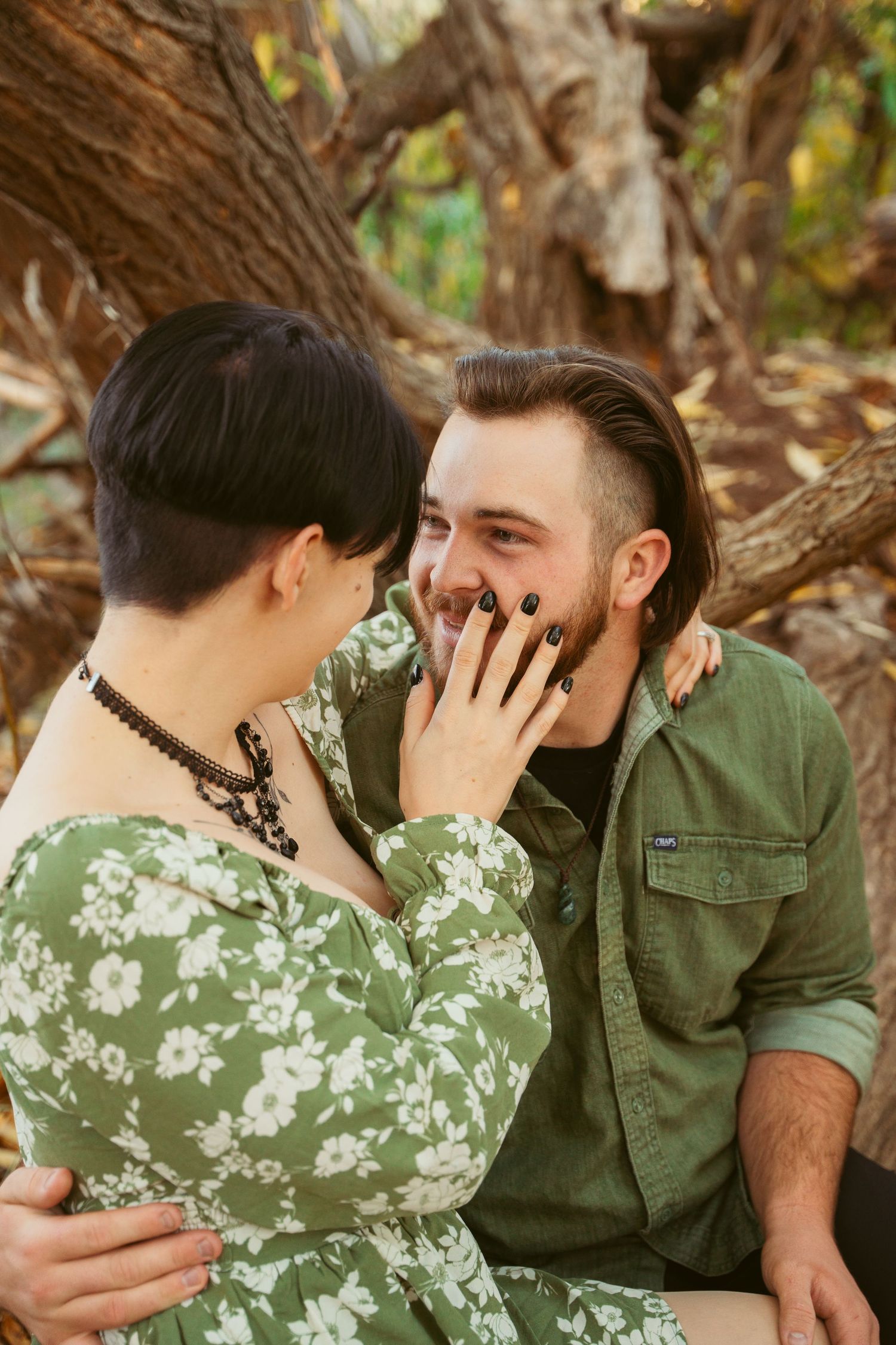 Intimate moments captured between couple in outdoor woodland setting.