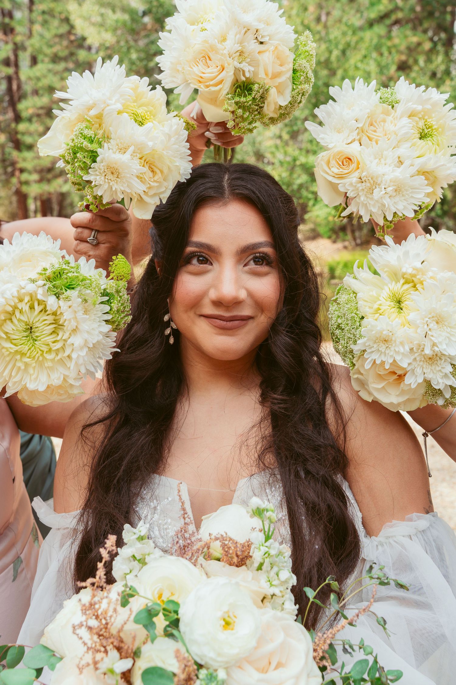 Joyful bride poses with white dahlias and roses in an outdoor garden setting.
