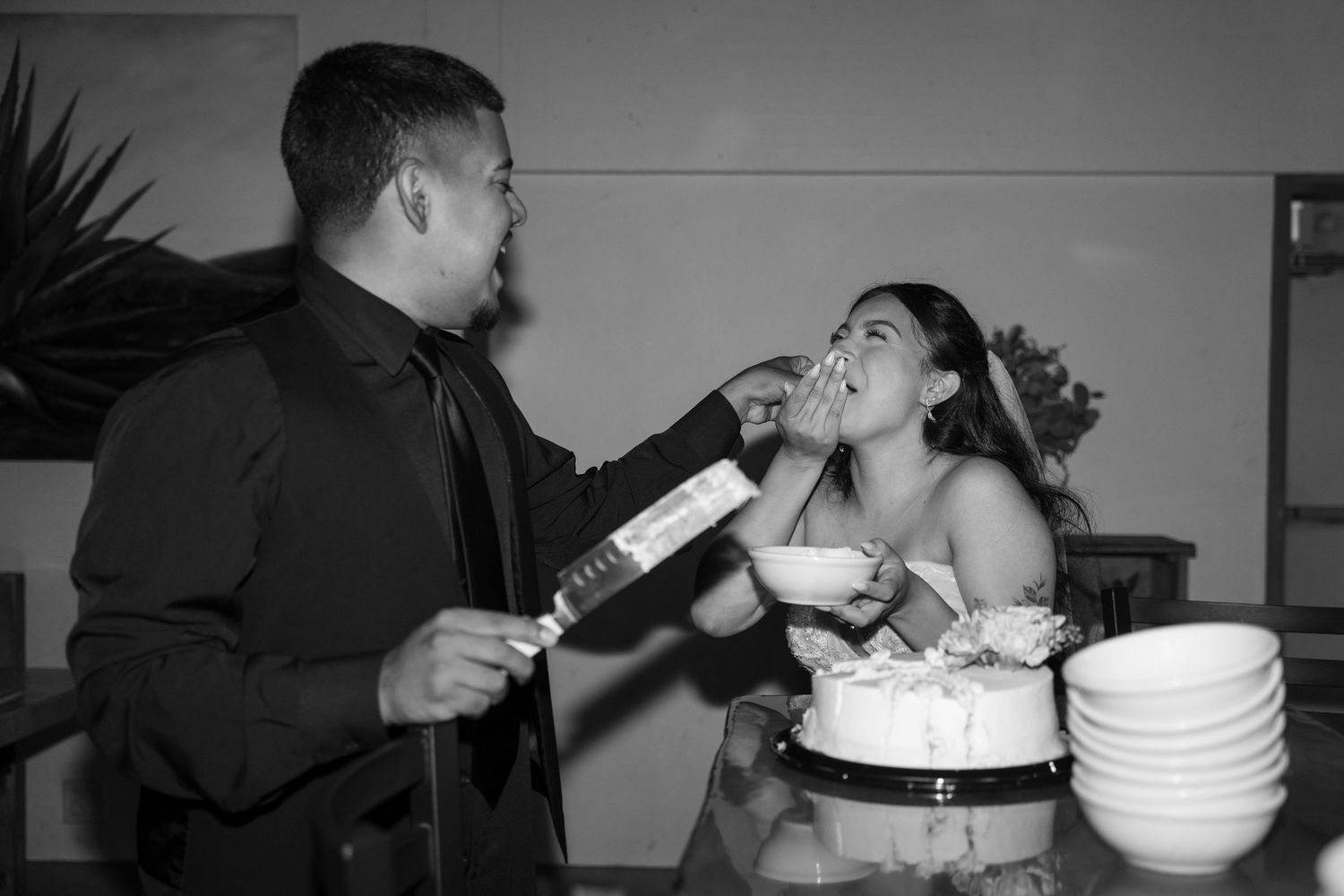 Black and white photo of newlyweds feeding each other wedding cake.