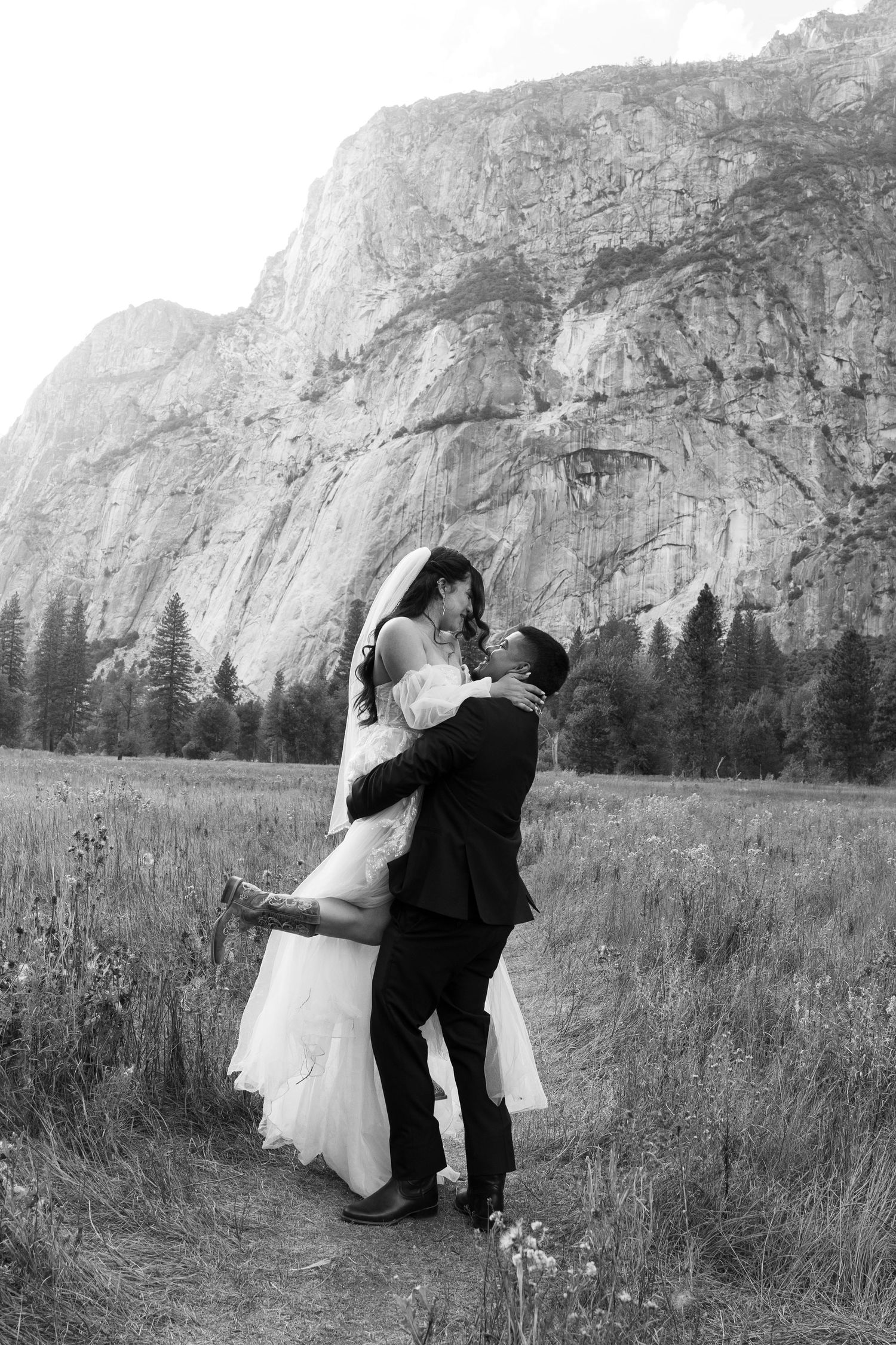 Black and white wedding portrait with dramatic mountain landscape in Yosemite Valley.