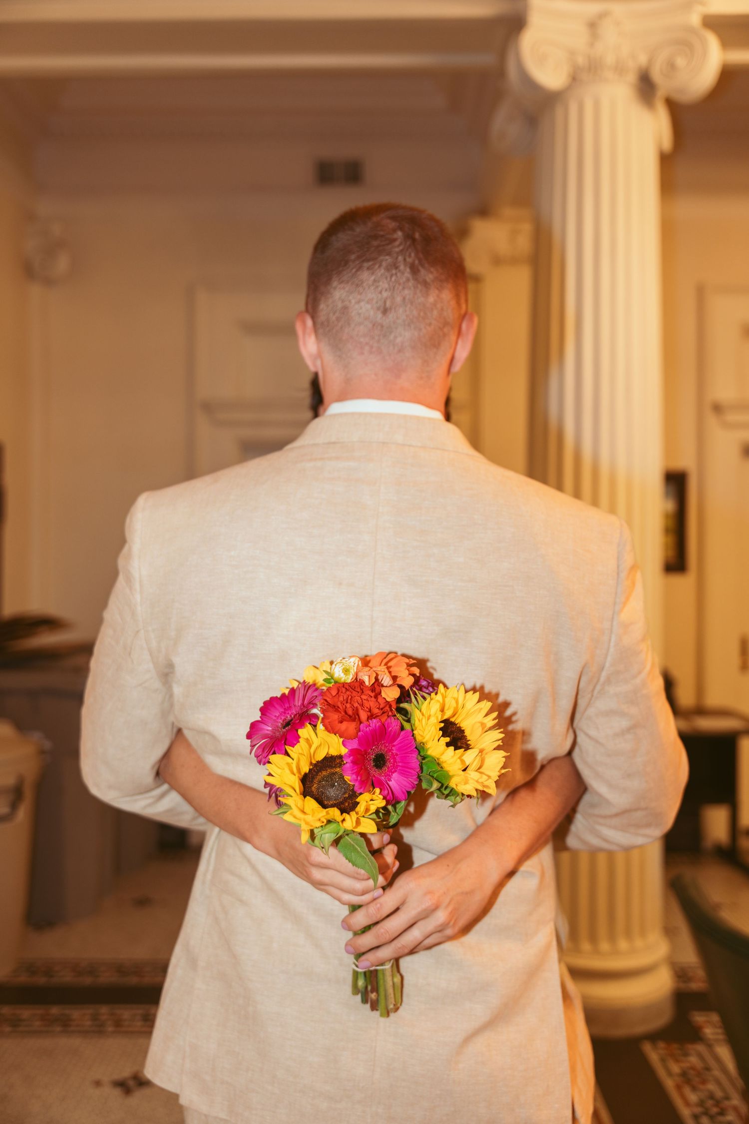 A sequence of photos showing someone hiding a vibrant bouquet of sunflowers and flowers behind their back.