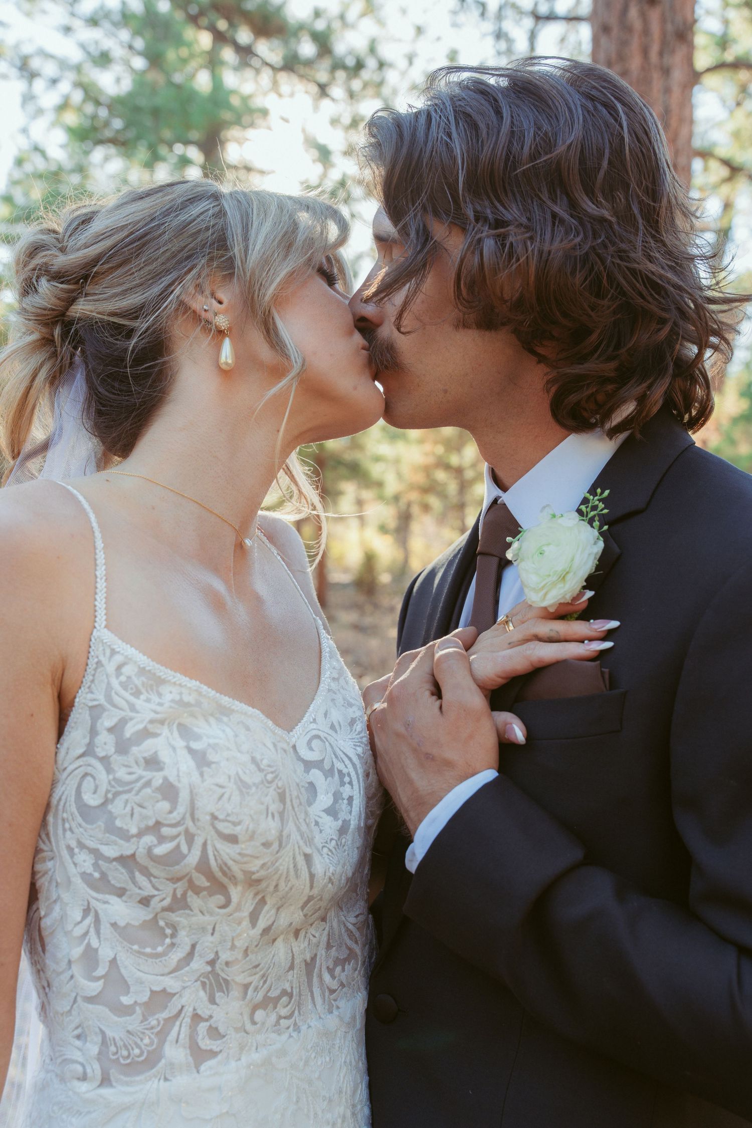 A tender wedding moment captured in a series of close-up shots among pine trees.