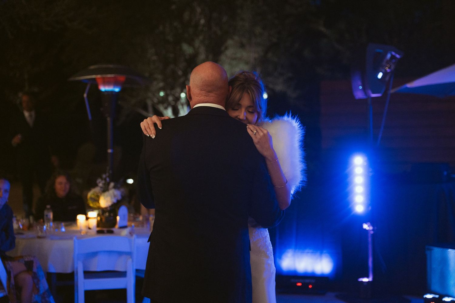 Wedding reception setup with blue mood lighting and elegant table decorations.