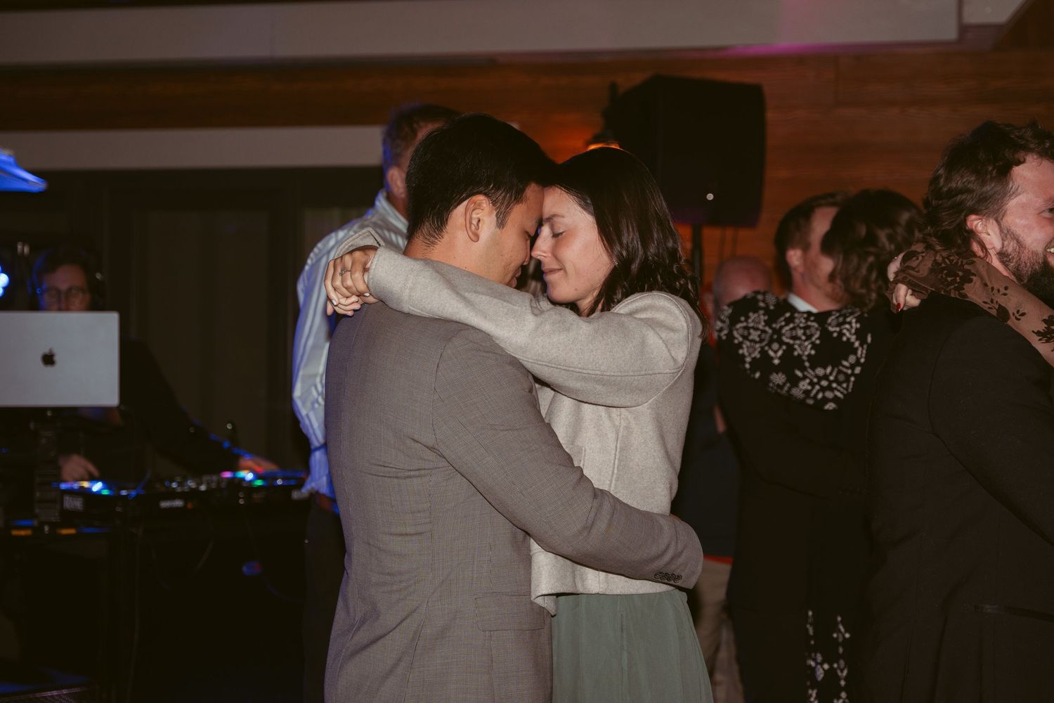 Couples dancing together at a dimly lit wedding reception venue.