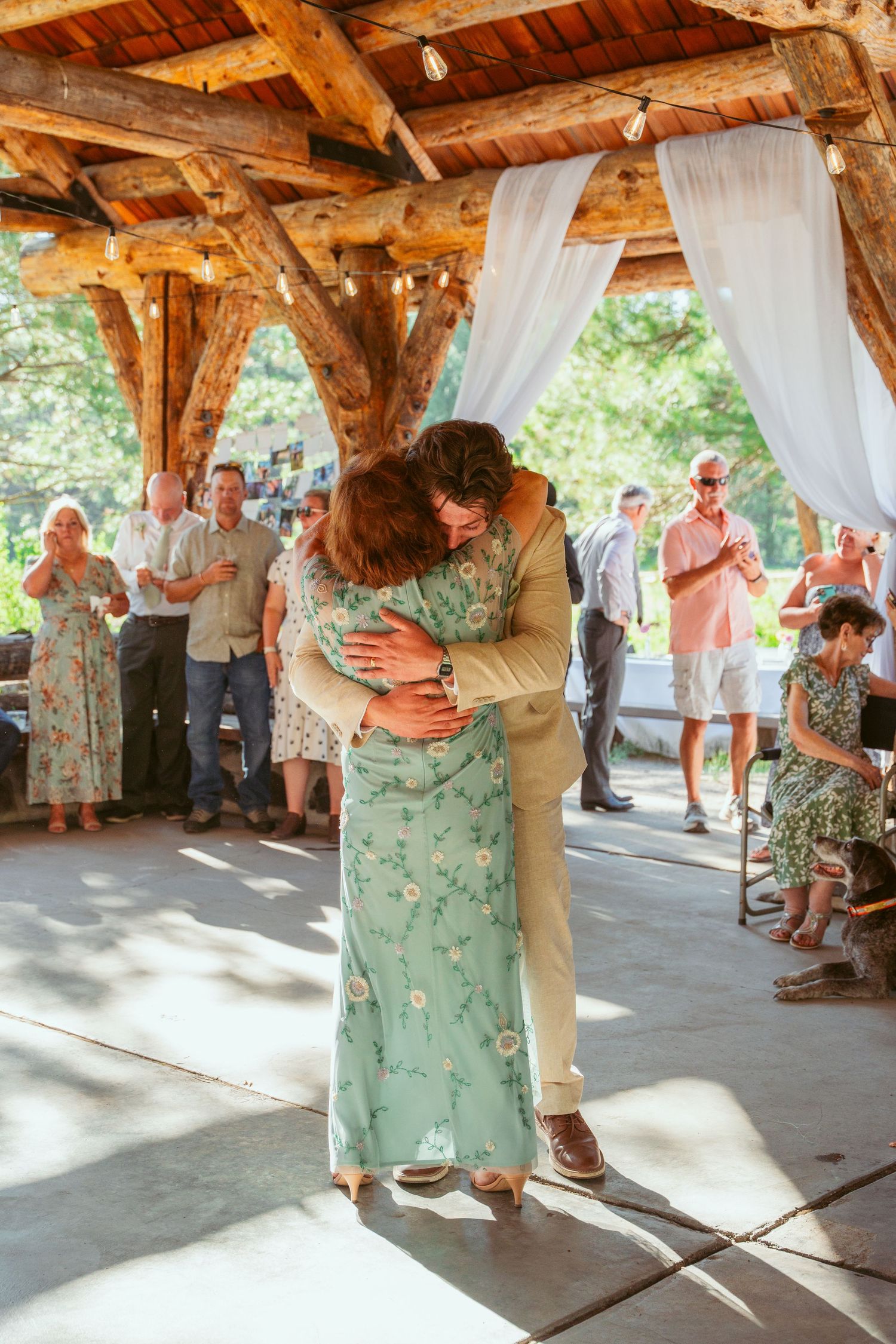 Wedding celebration dance in timber frame pavilion with guests watching.