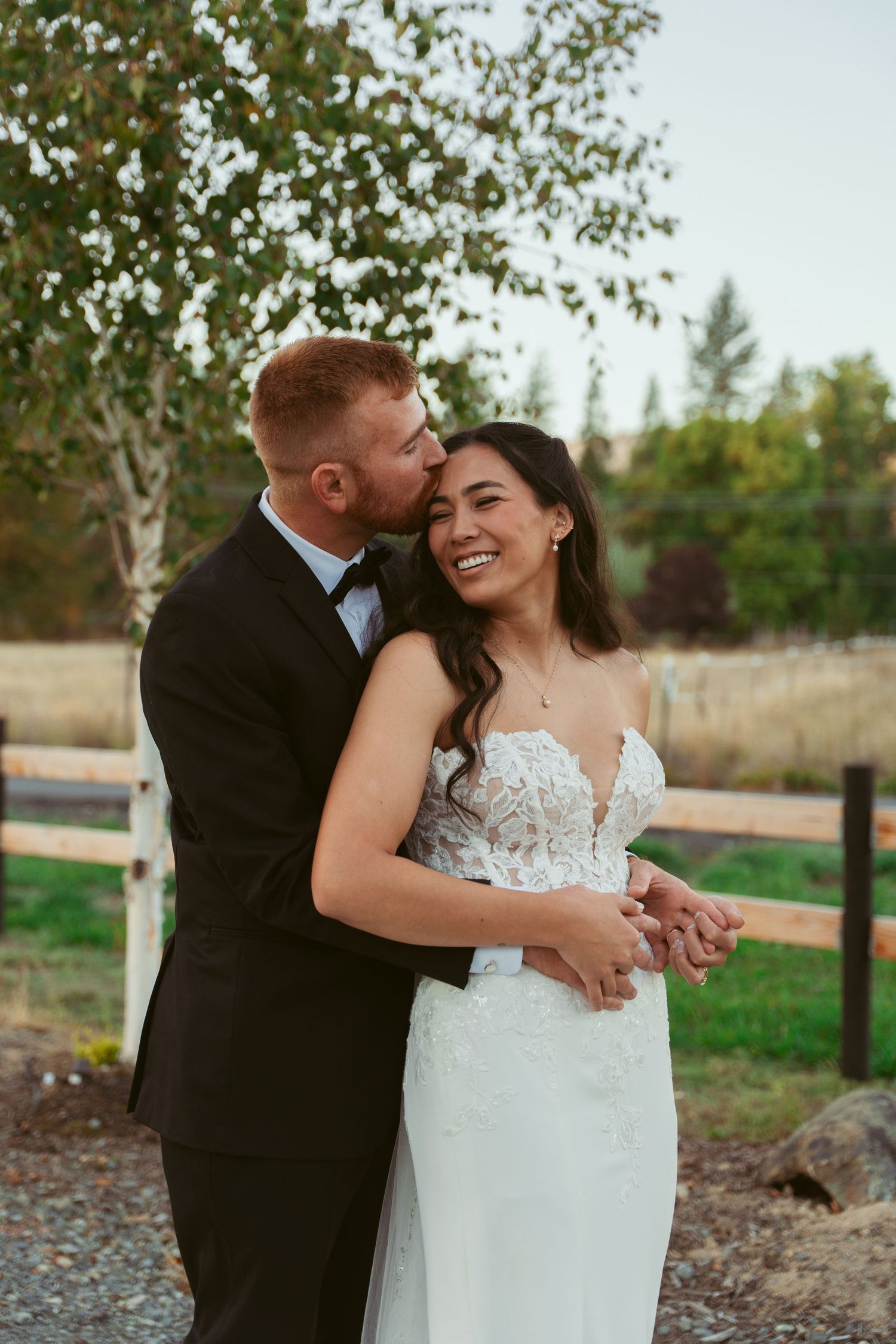 Intimate outdoor wedding portrait of couple embracing at sunset.