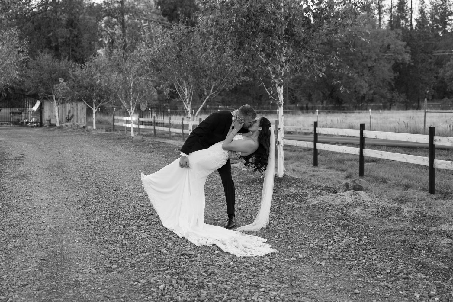 Black and white wedding photo of couple walking together on a scenic path.