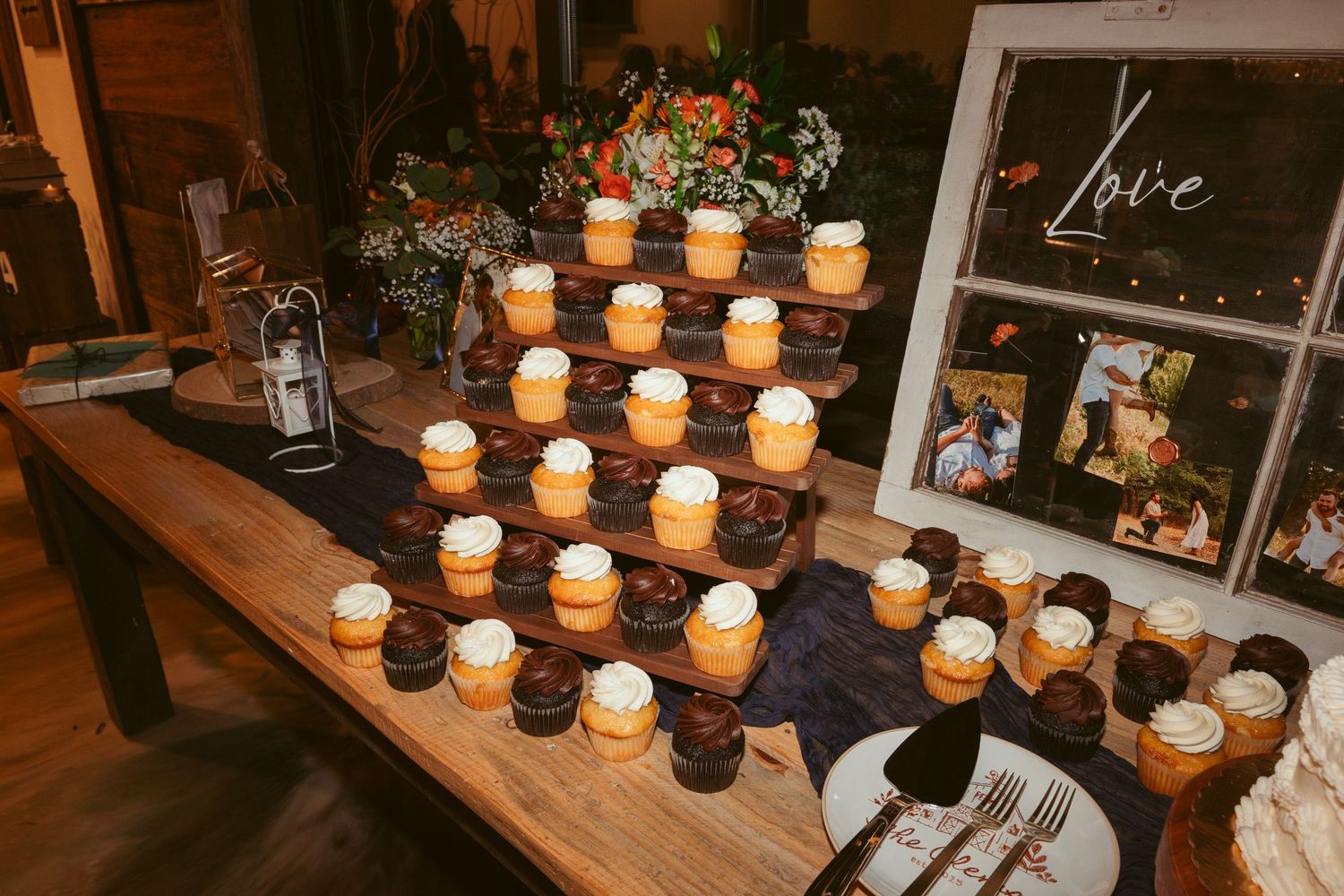 Rustic wooden table decorated with glowing mason jar candles and framed photos for wedding reception.
