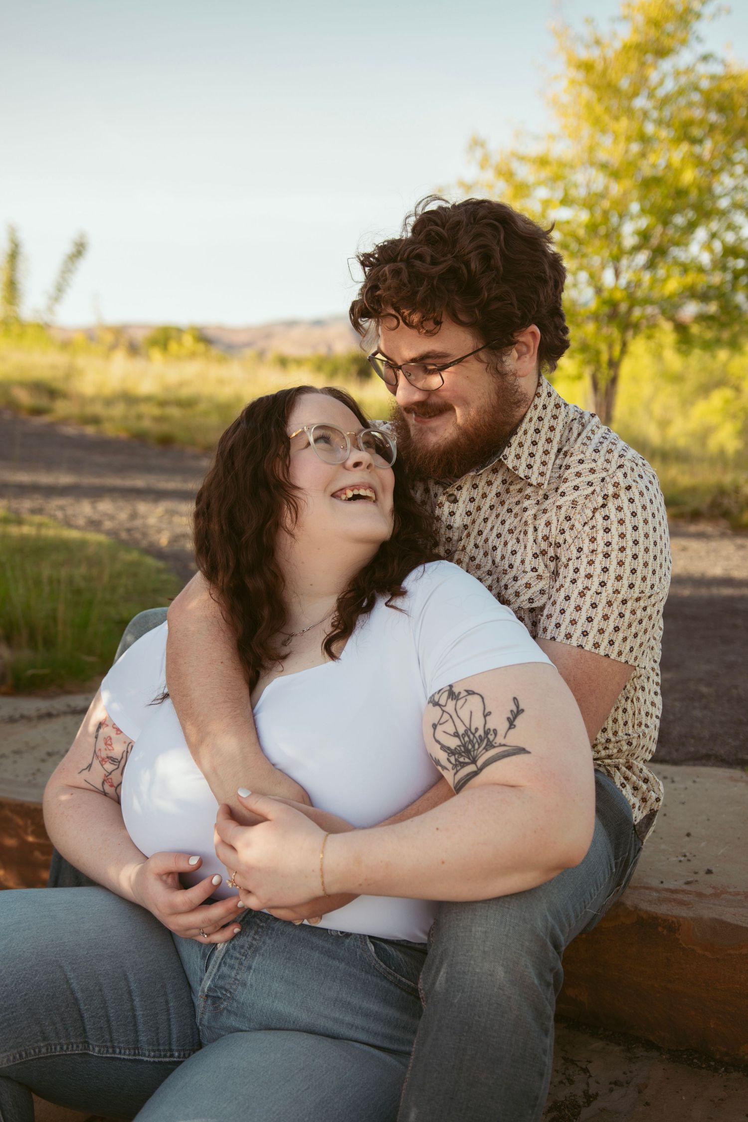 A couple shares an intimate moment while sitting outdoors in autumn scenery.