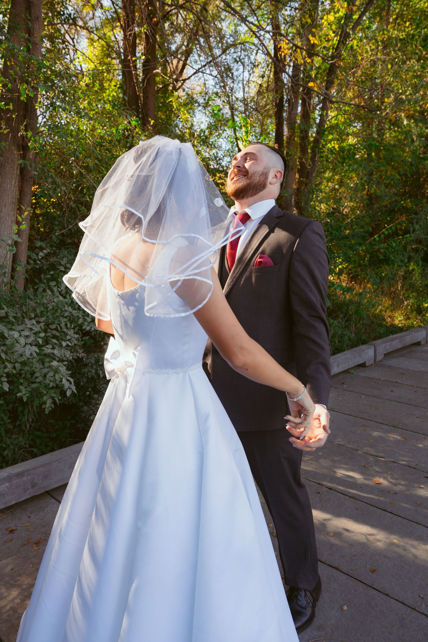 A couple shares a romantic moment on their wedding day in a wooded setting.