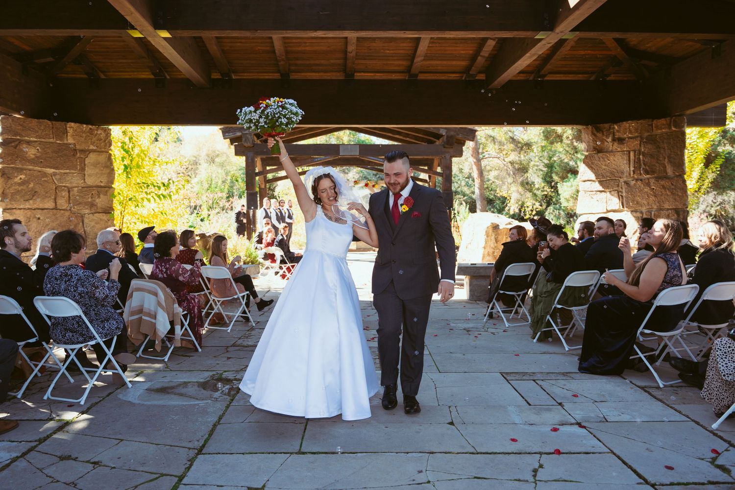Wide shot of a covered outdoor wedding space with wooden beams and stone architecture.