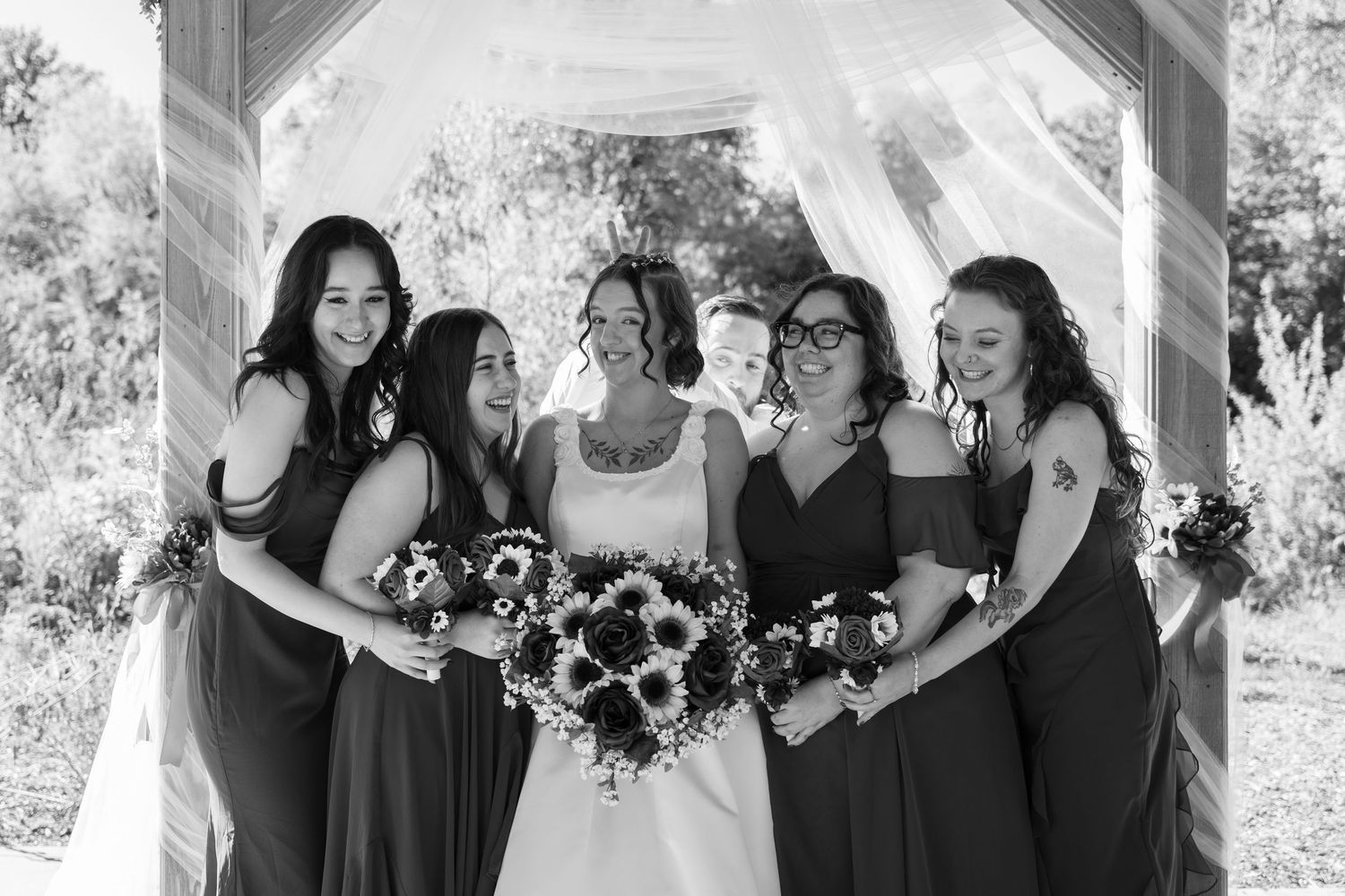 Black and white photo of bridal party sharing laughs during wedding photoshoot.