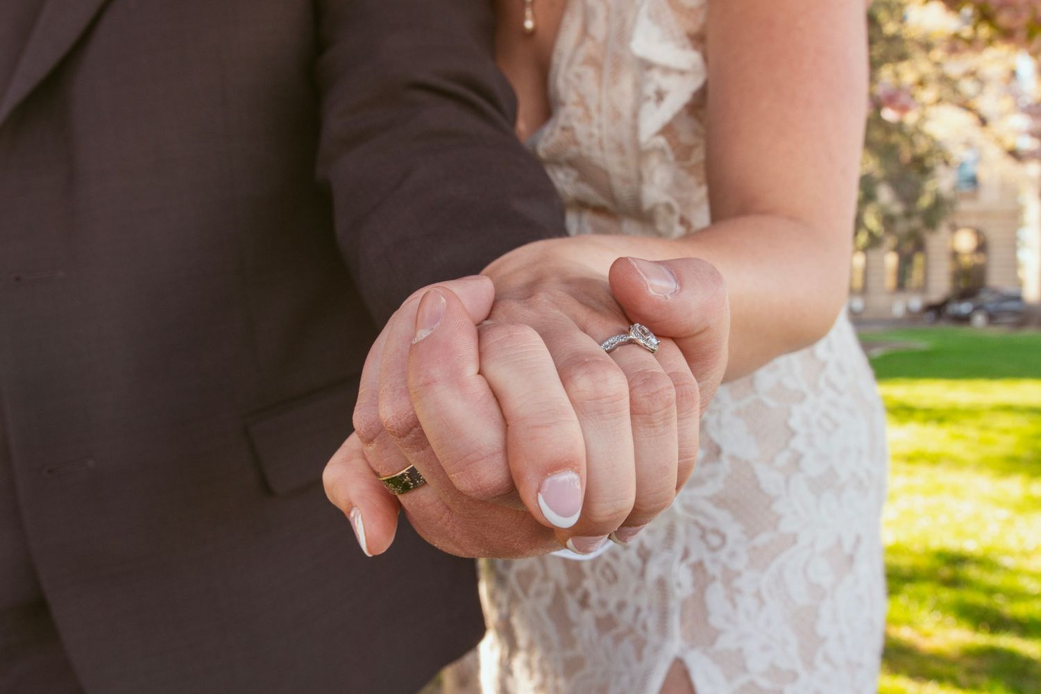 Close-up of couple's hands during wedding ceremony showing rings and formal attire.