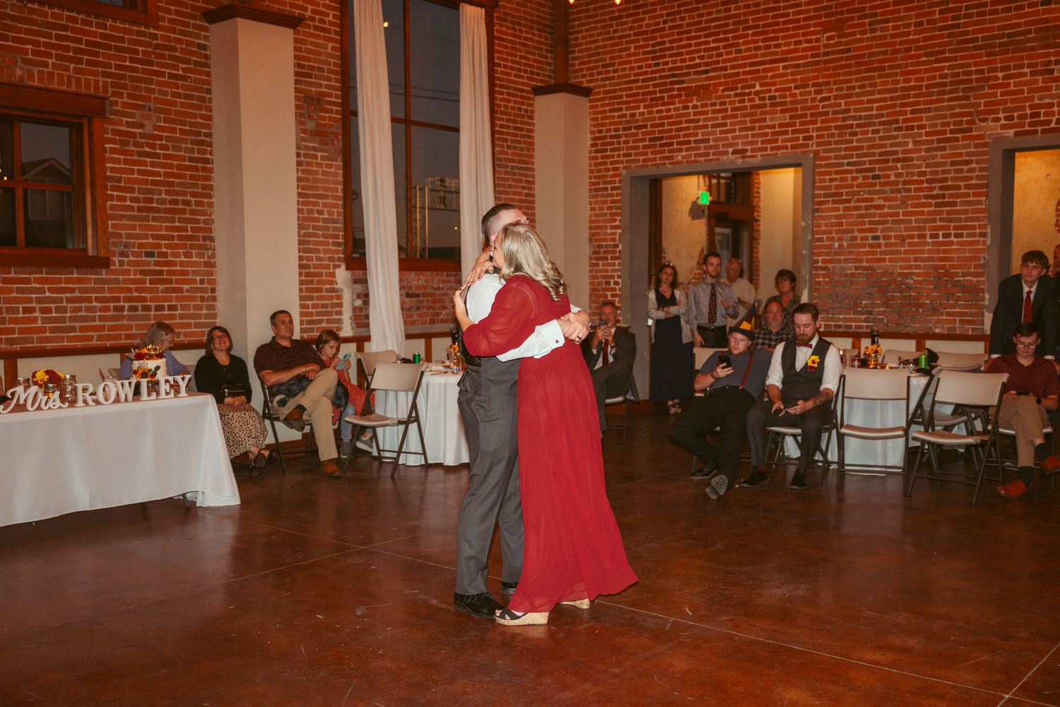 Dance floor scene in rustic brick venue with white curtains and ambient lighting.
