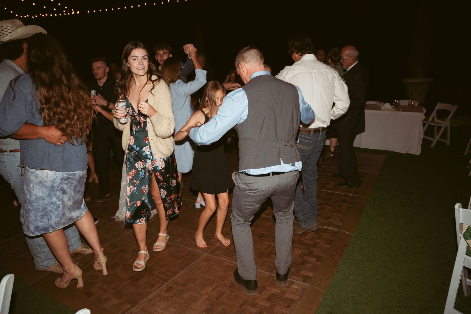 Guests dancing and moving on an outdoor dance floor during a nighttime celebration.