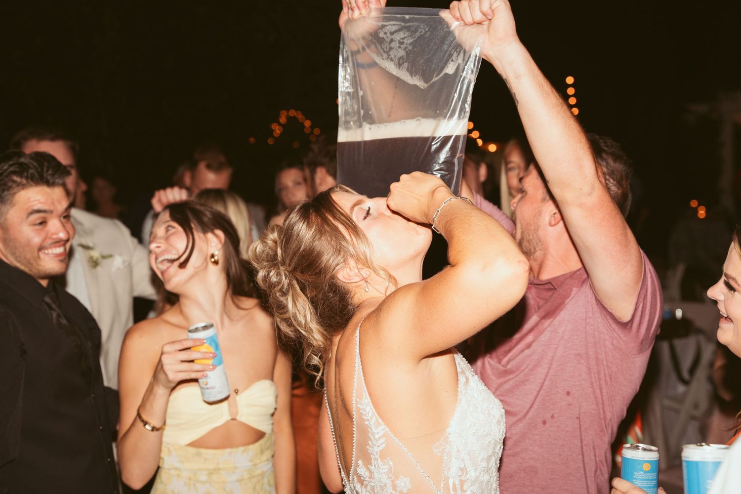 Party guests enjoying drinks and dancing at nighttime celebration.