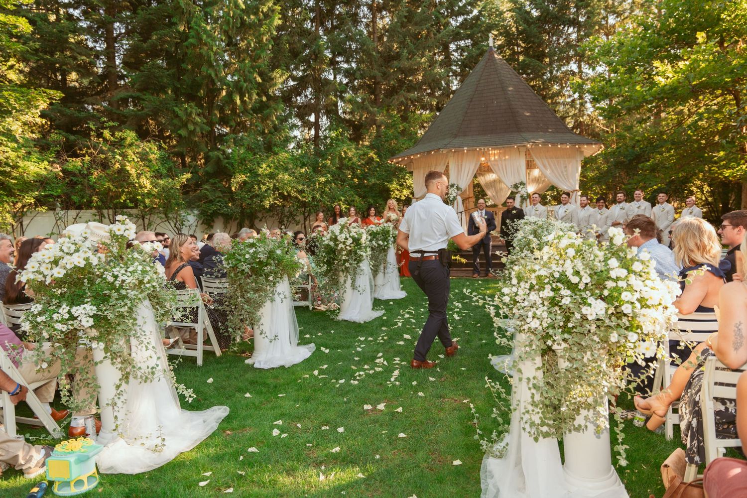 Wedding ceremony guests celebrate with flower petals in an outdoor garden setting.