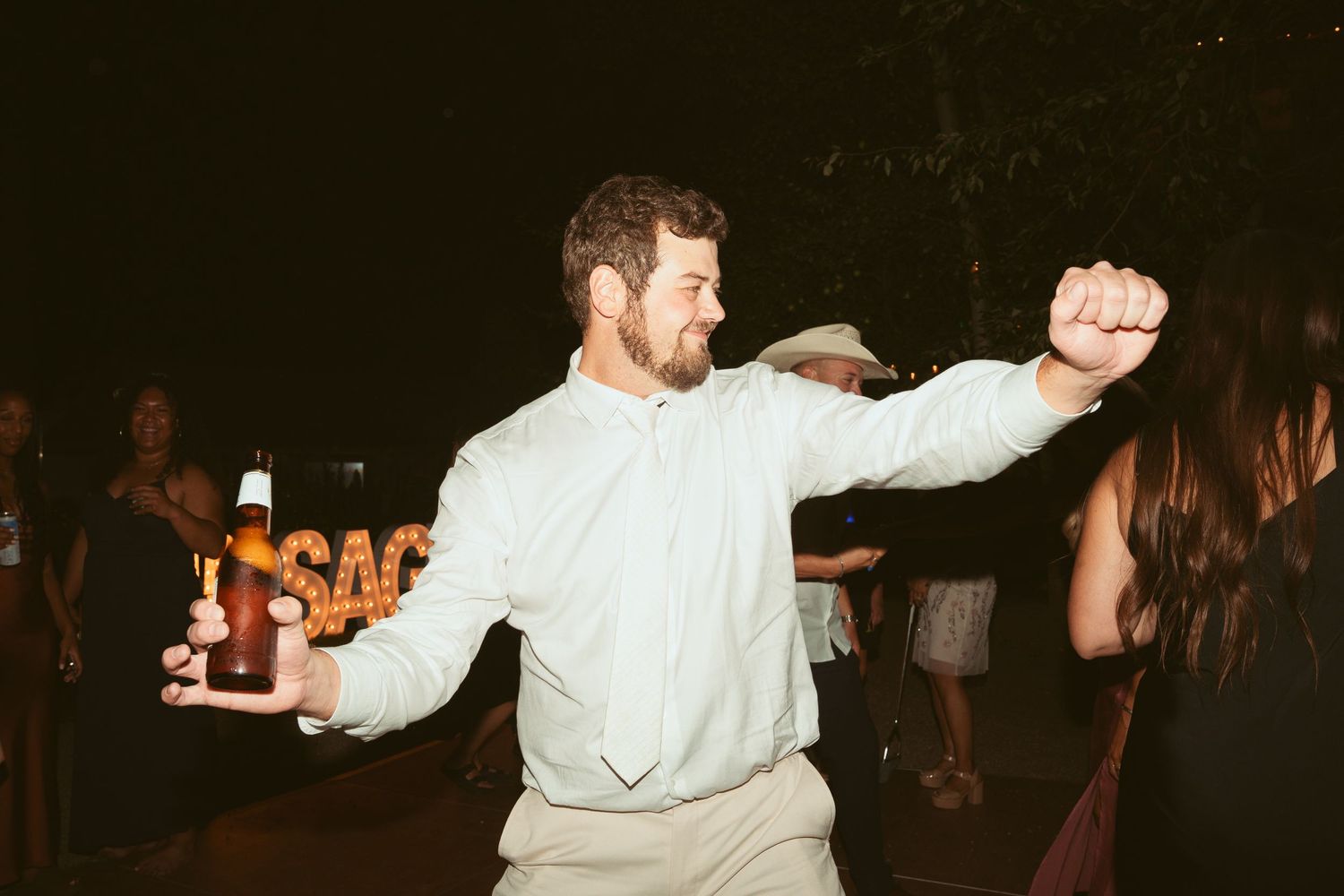 Wedding guests dancing energetically at an evening outdoor celebration.