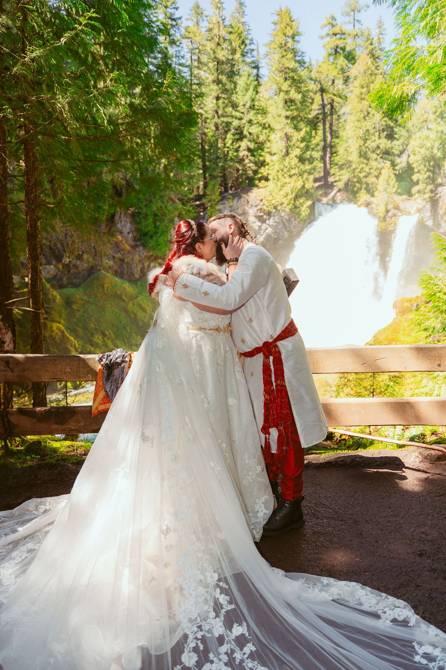 A flowing white wedding dress with long train captured in a forest setting.