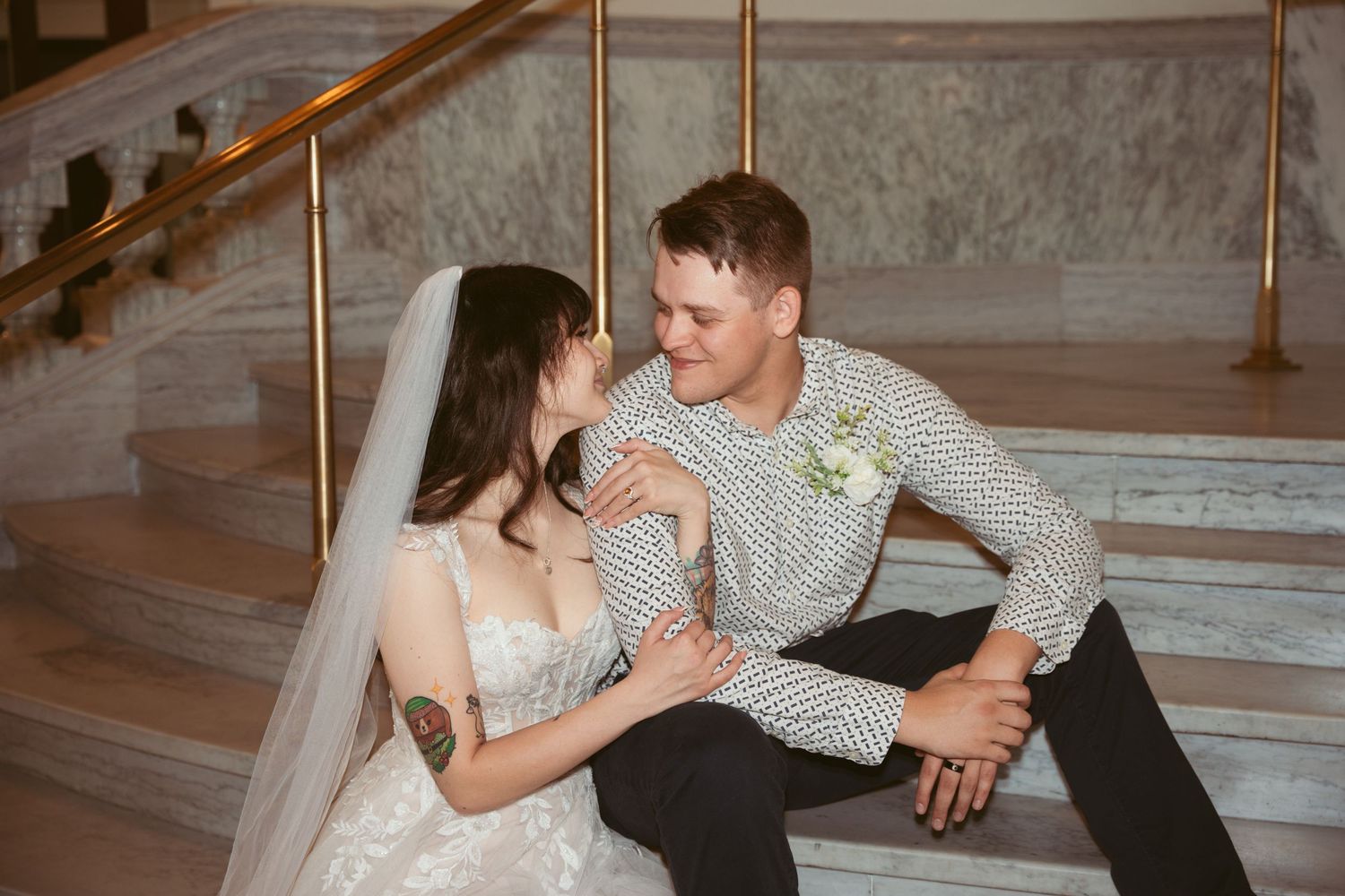 Couple shares tender moment while sitting on elegant marble steps indoors.