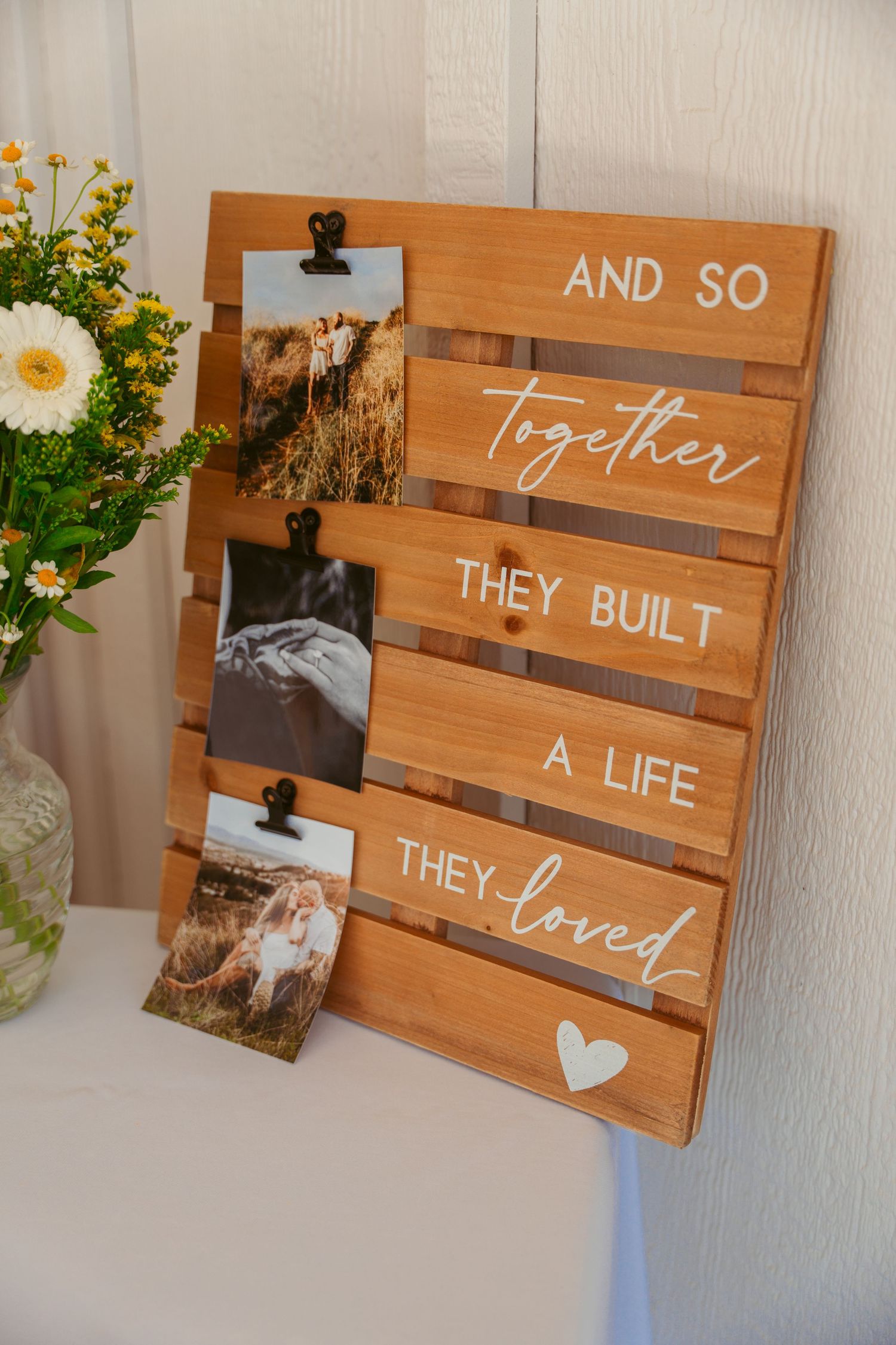 Wooden pallet signs with romantic quotes and hearts displayed at a wedding.