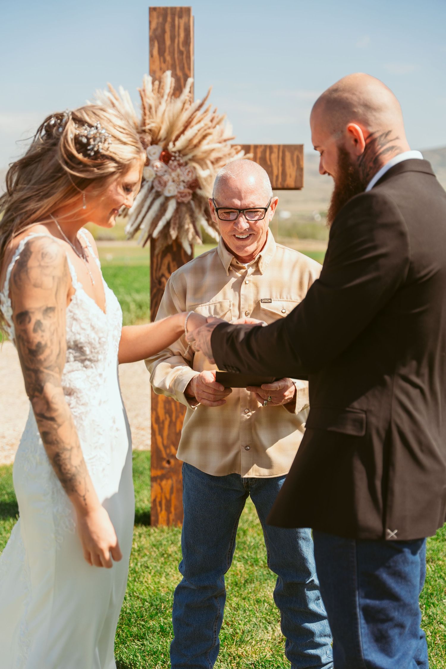 Wedding ceremony interaction between couple near wooden post in mountain landscape.