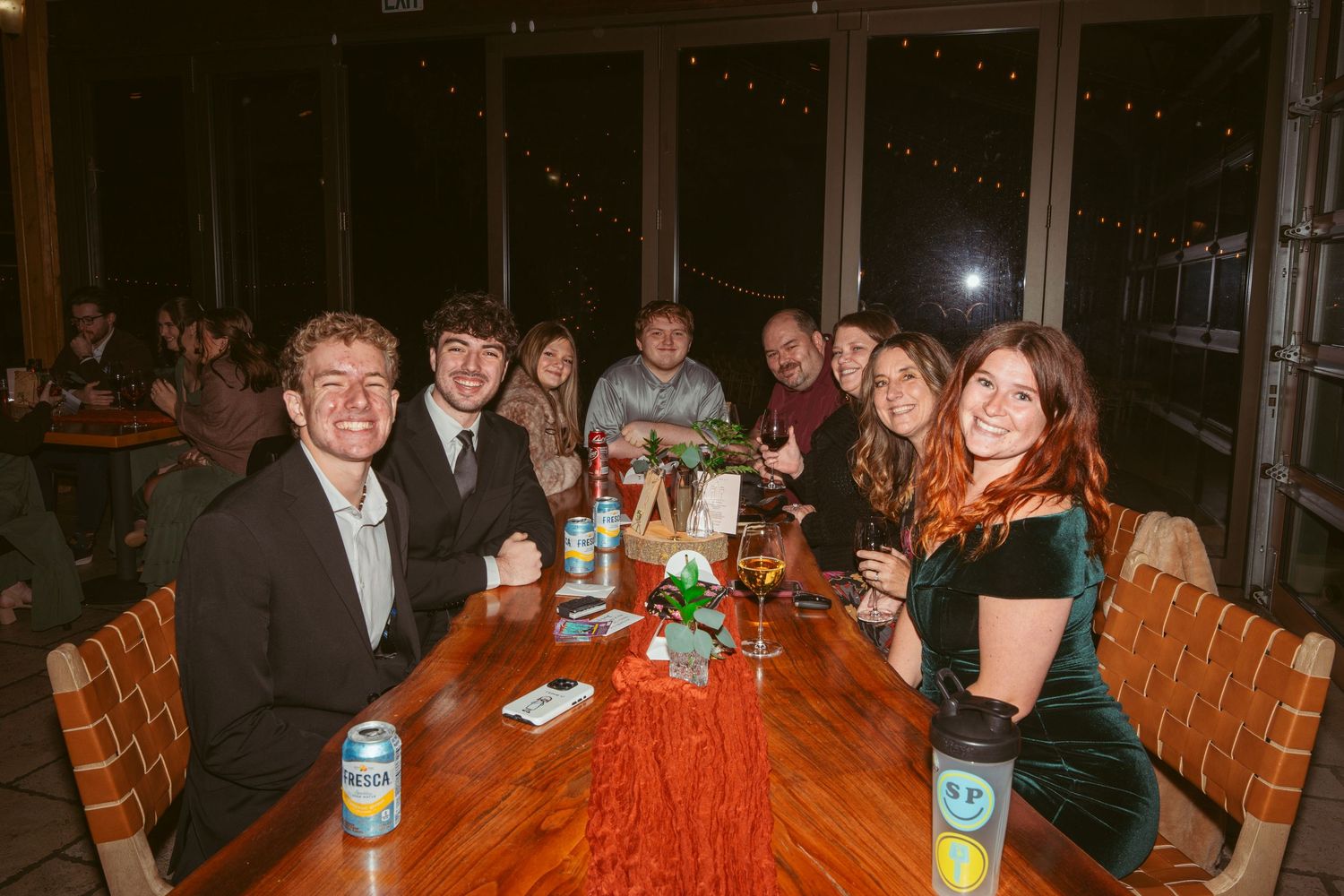 Guests socializing at round wooden tables during an evening gathering.