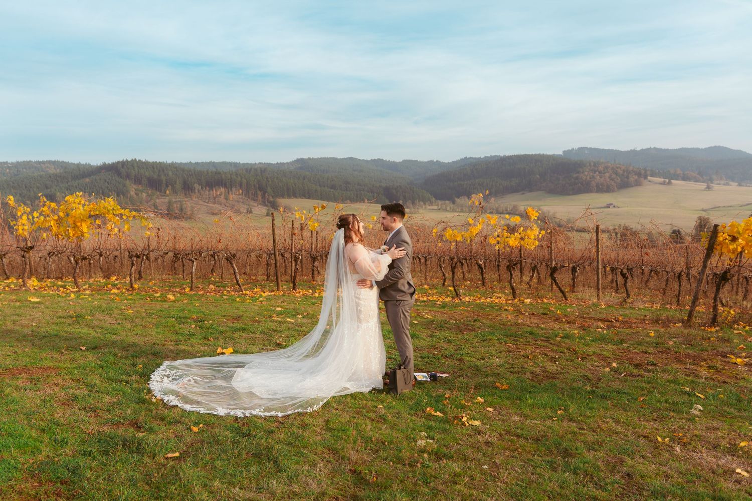 Scenic vineyard wedding photo with rolling hills and fall foliage.